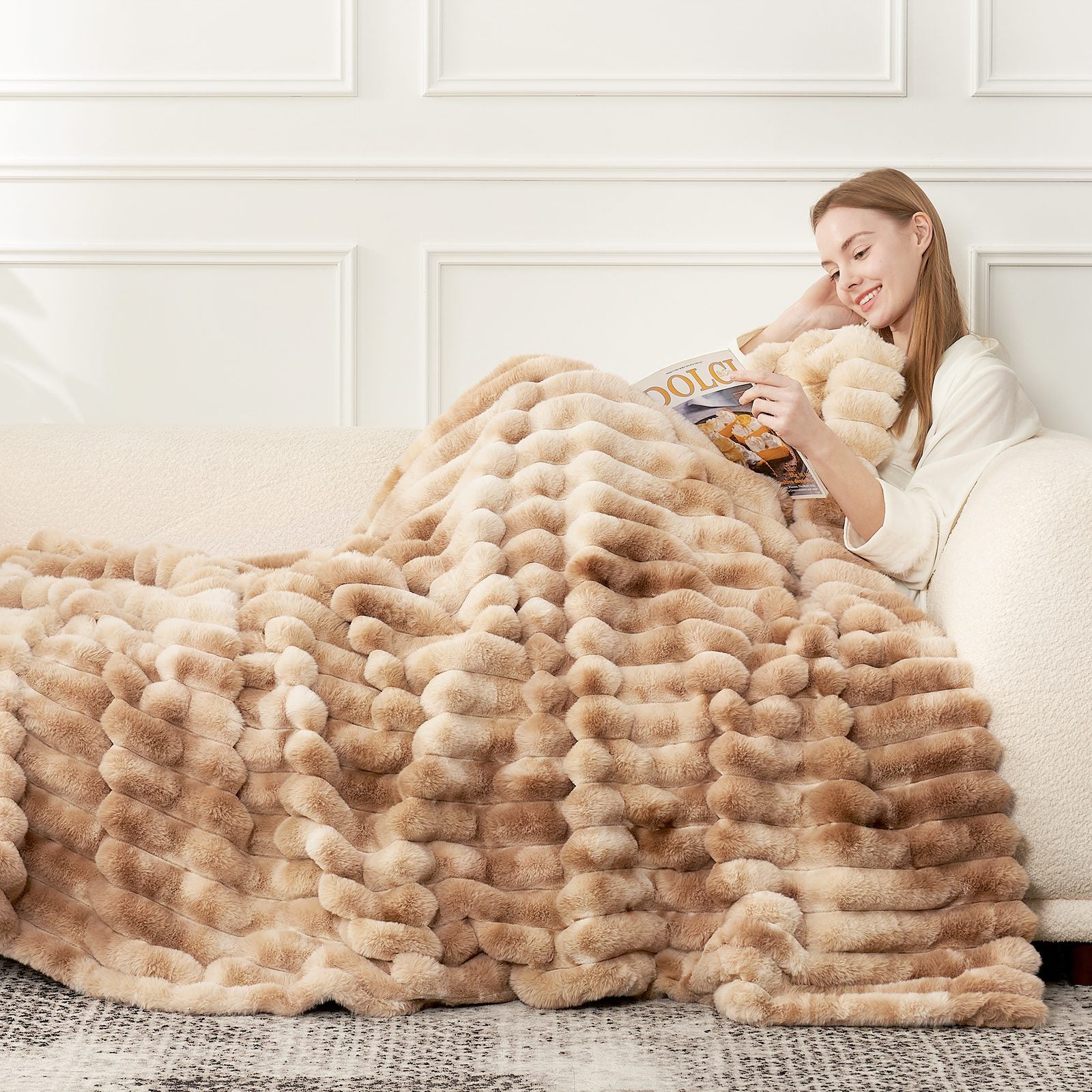 Striped faux fur blanket in beige with a woman reading. Cozy bedding for luxurious comfort. #color_Tie-dye Khaki