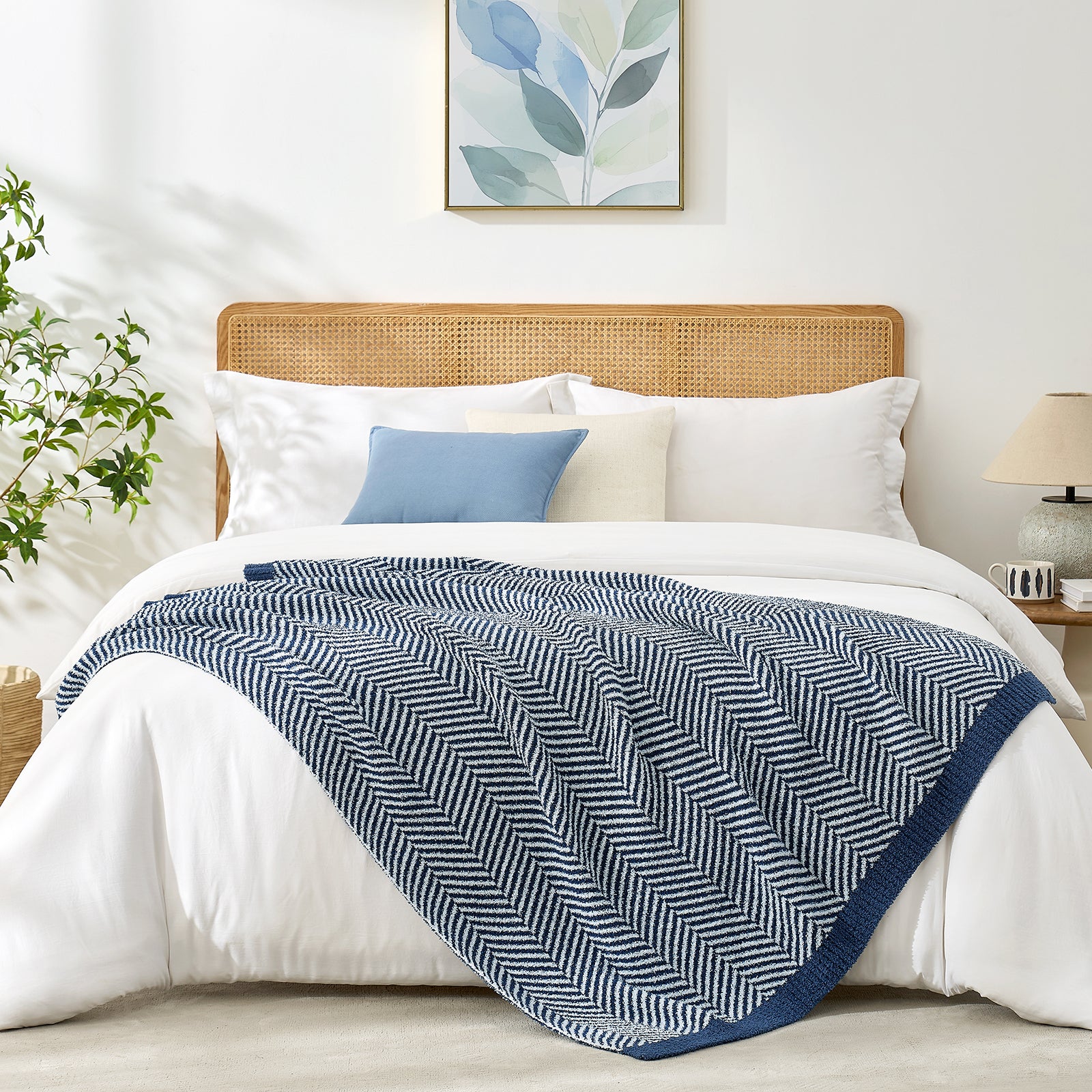 Reversible herringbone feather yarn knit throw blanket styled across a modern white bed #color_Navy Blue