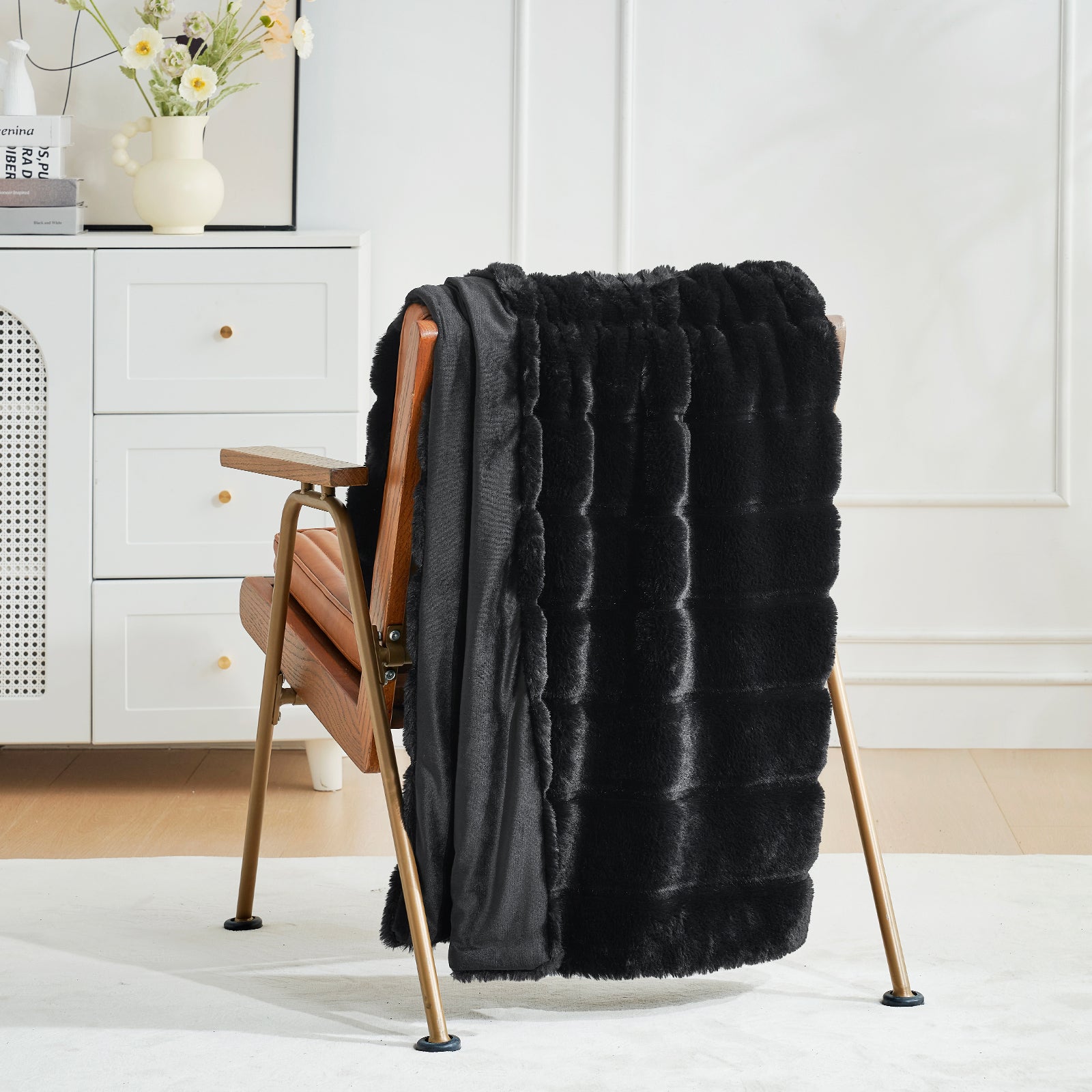 Black faux fur throw blanket draped over a wooden chair in a room with white walls and decor. #color_Black