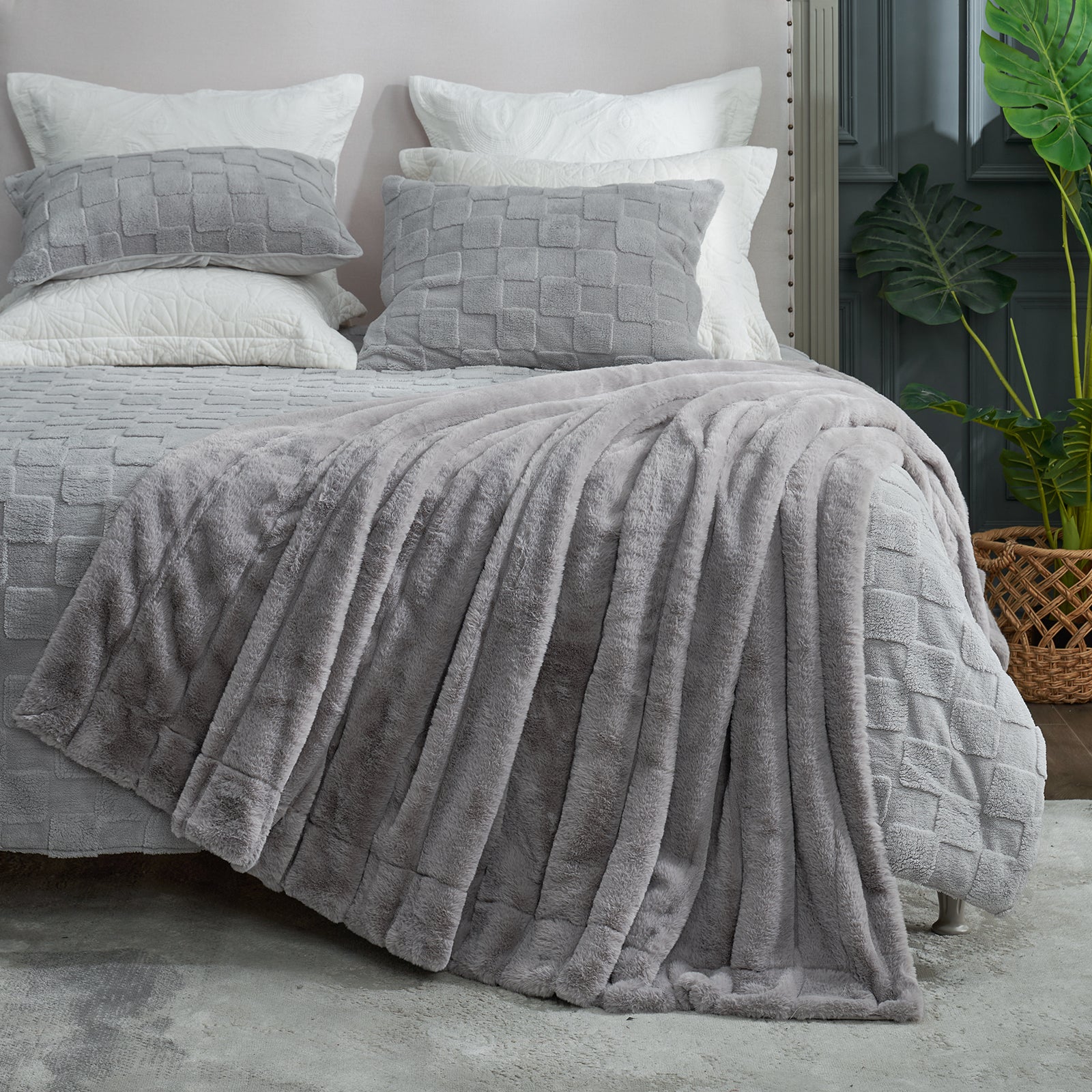 Gray textured bedding set on a bed with pillows and a plant in the background. #color_Grey