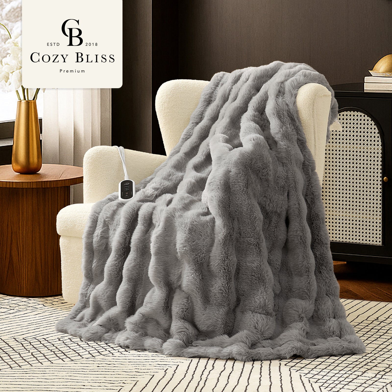 Woman sitting on a couch with a gray fuzzy blanket wrapped around her, using a laptop. #color_Light Grey