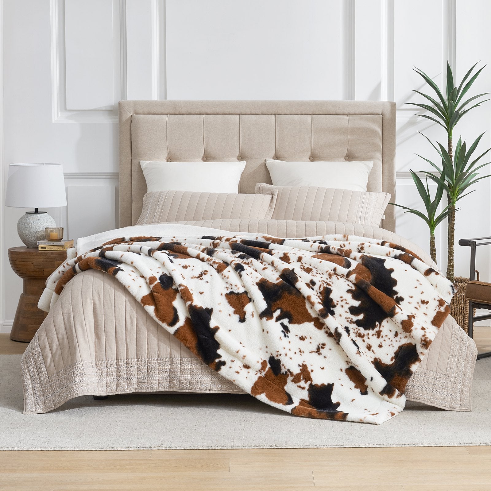 Cow print faux fur blanket on bed, stylish and cozy bedding for home decor. #color_Black/Brown