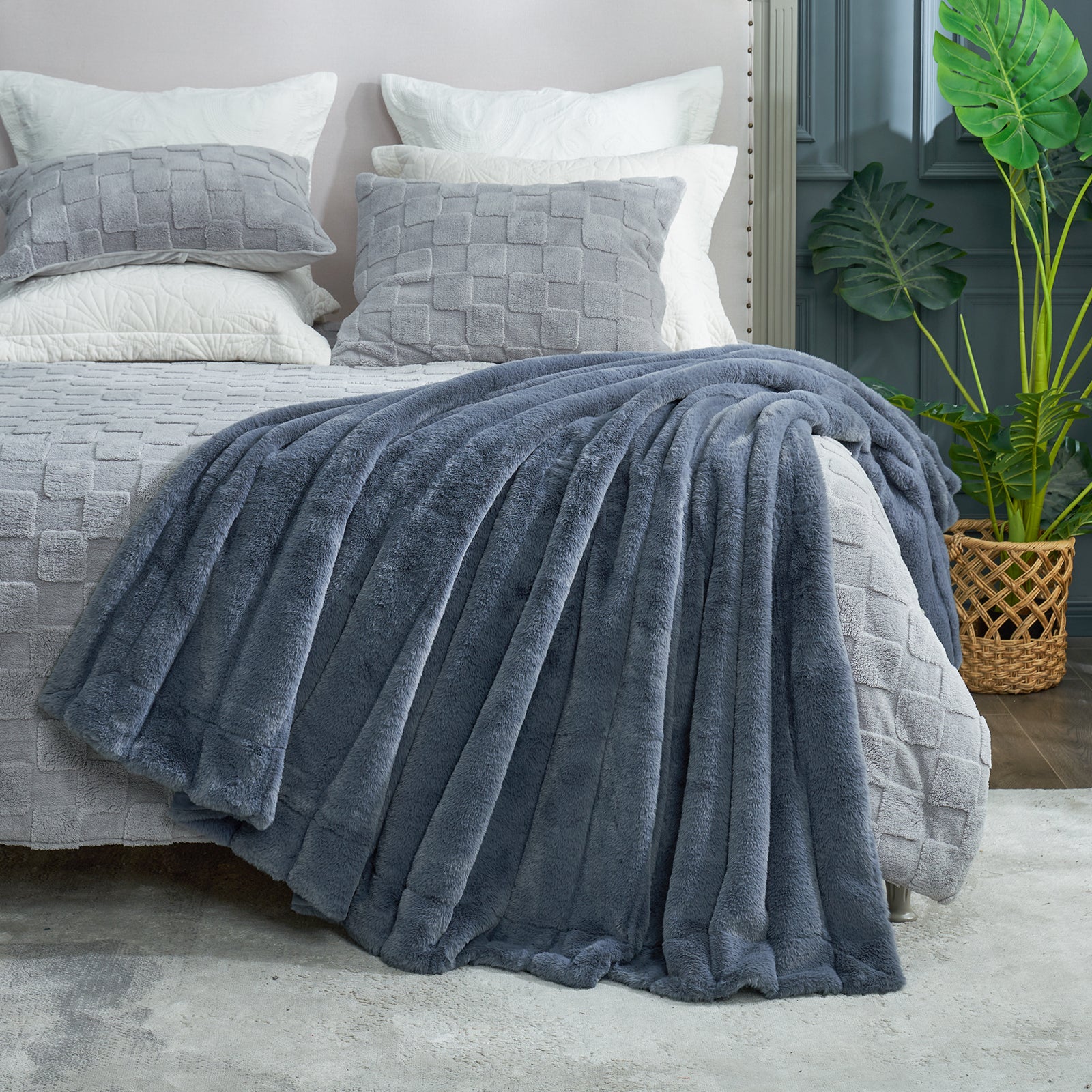 Gray textured blanket draped over a bed with matching pillows, in a bedroom setting. #color_Blue