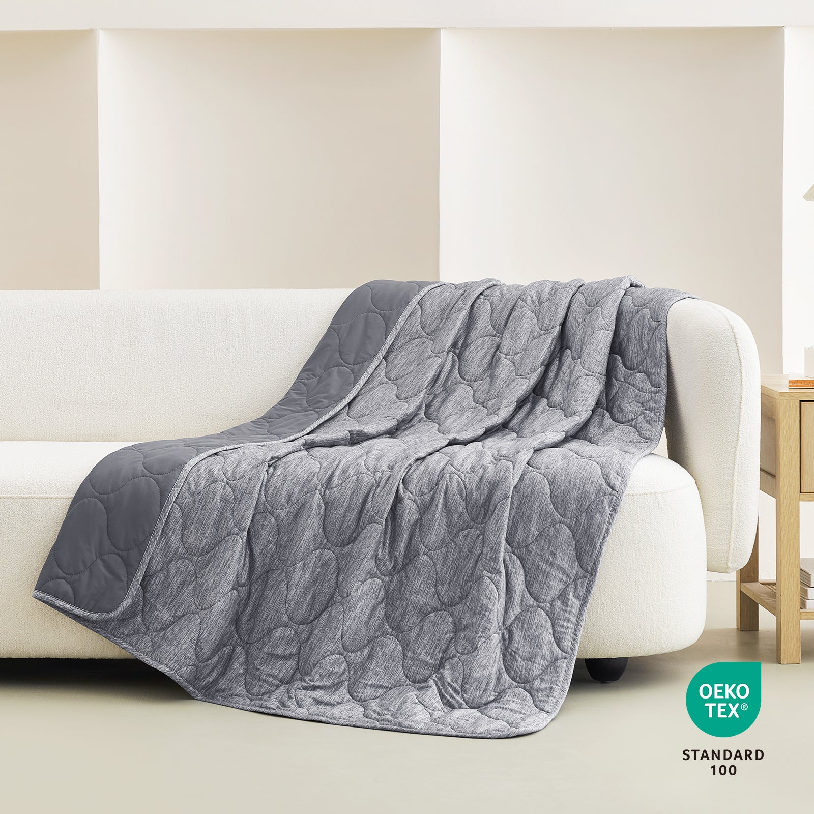 Gray Cozy Bliss dual-sided cooling blanket with cloud pattern, OEKO-TEX certified, draped on a sofa. #color_Charcoal Grey