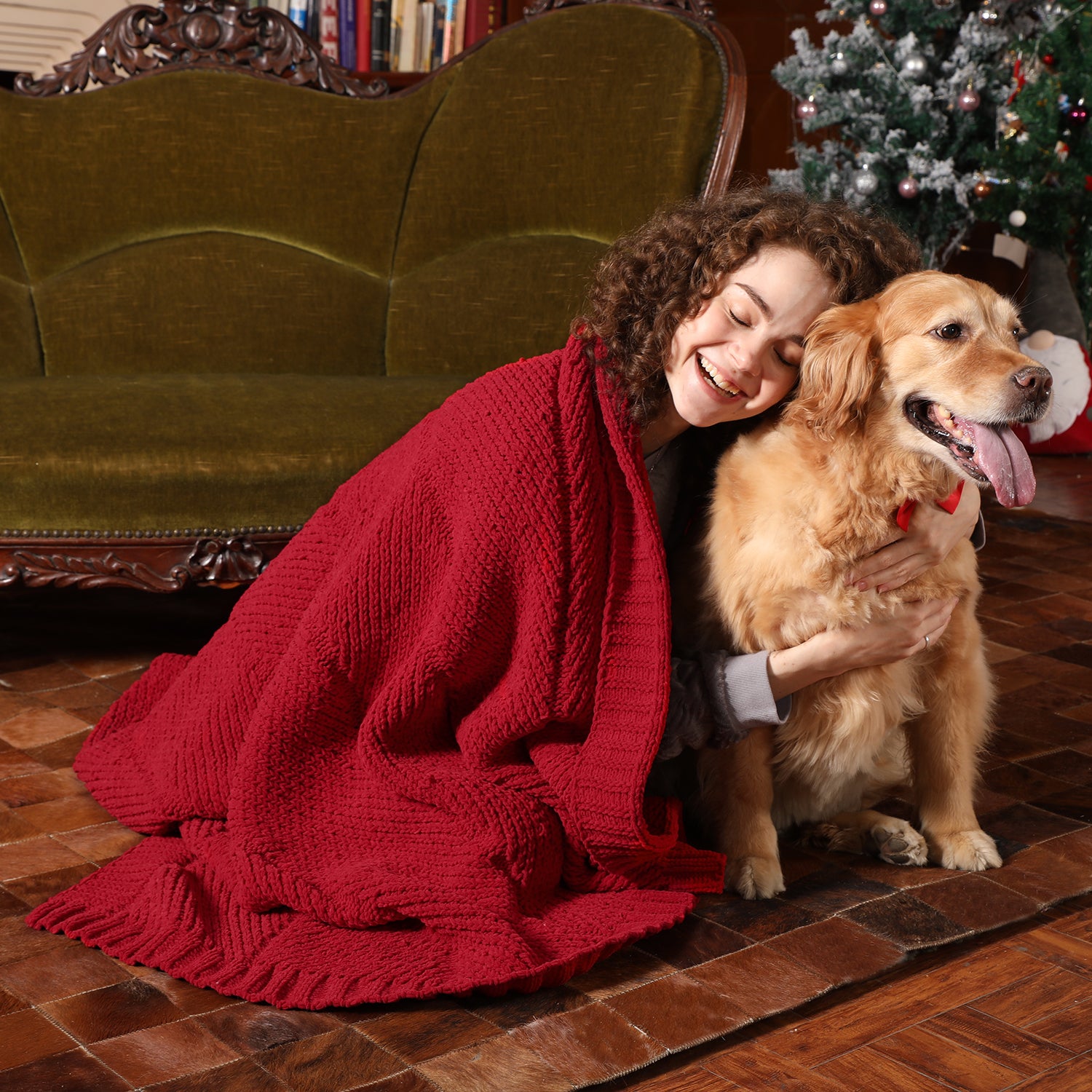 Woman hugging a golden dog with a red blanket in a cozy living room. #color_Christmas Red