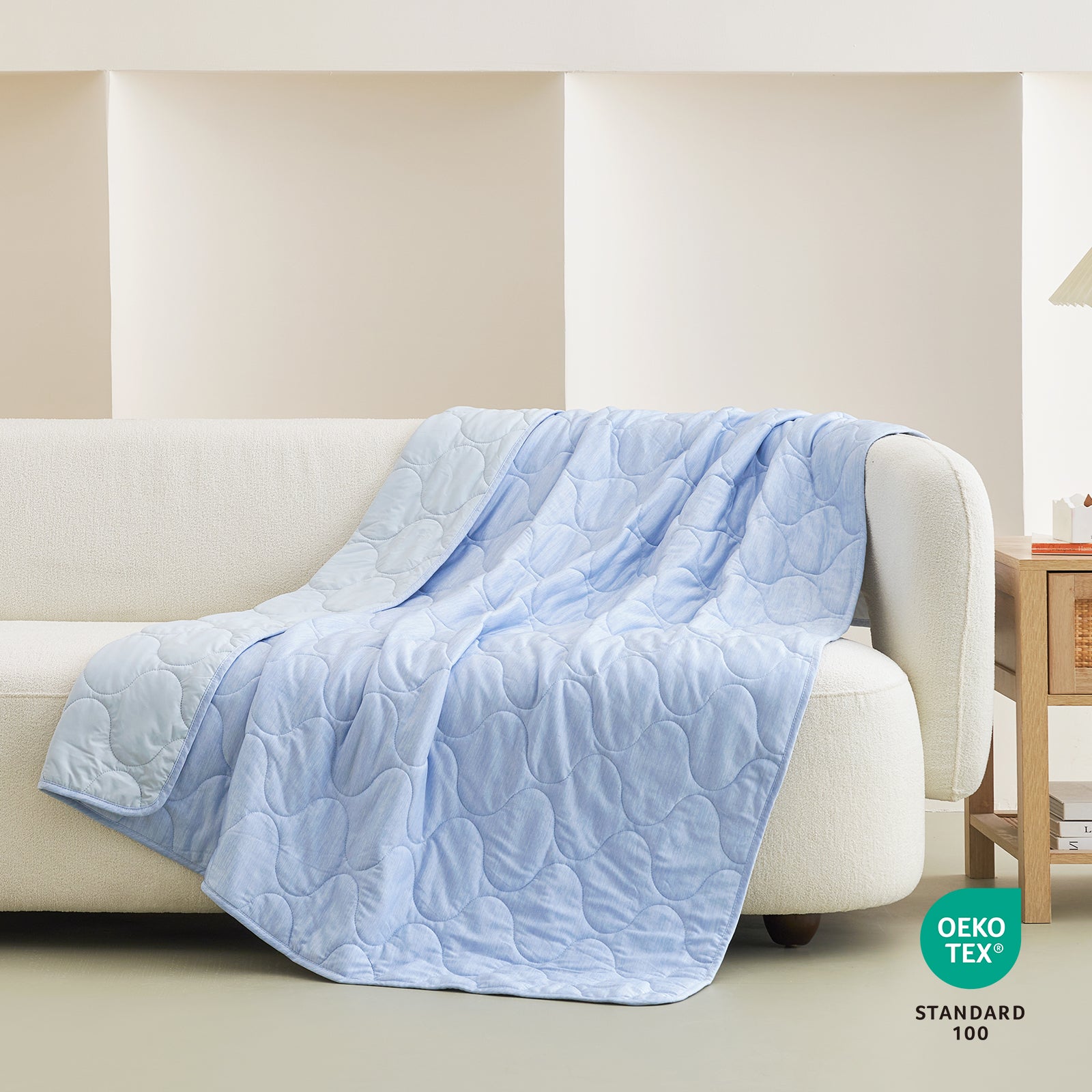 Light blue cooling blanket with cloud pattern draped on a white sofa, OEKO-TEX certified, cozy bedding #color_Cool Blue