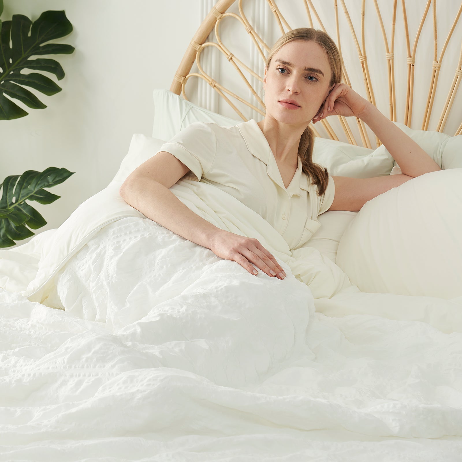 Woman resting on a bed with a white seersucker cooling comforter #Color_White Plaid