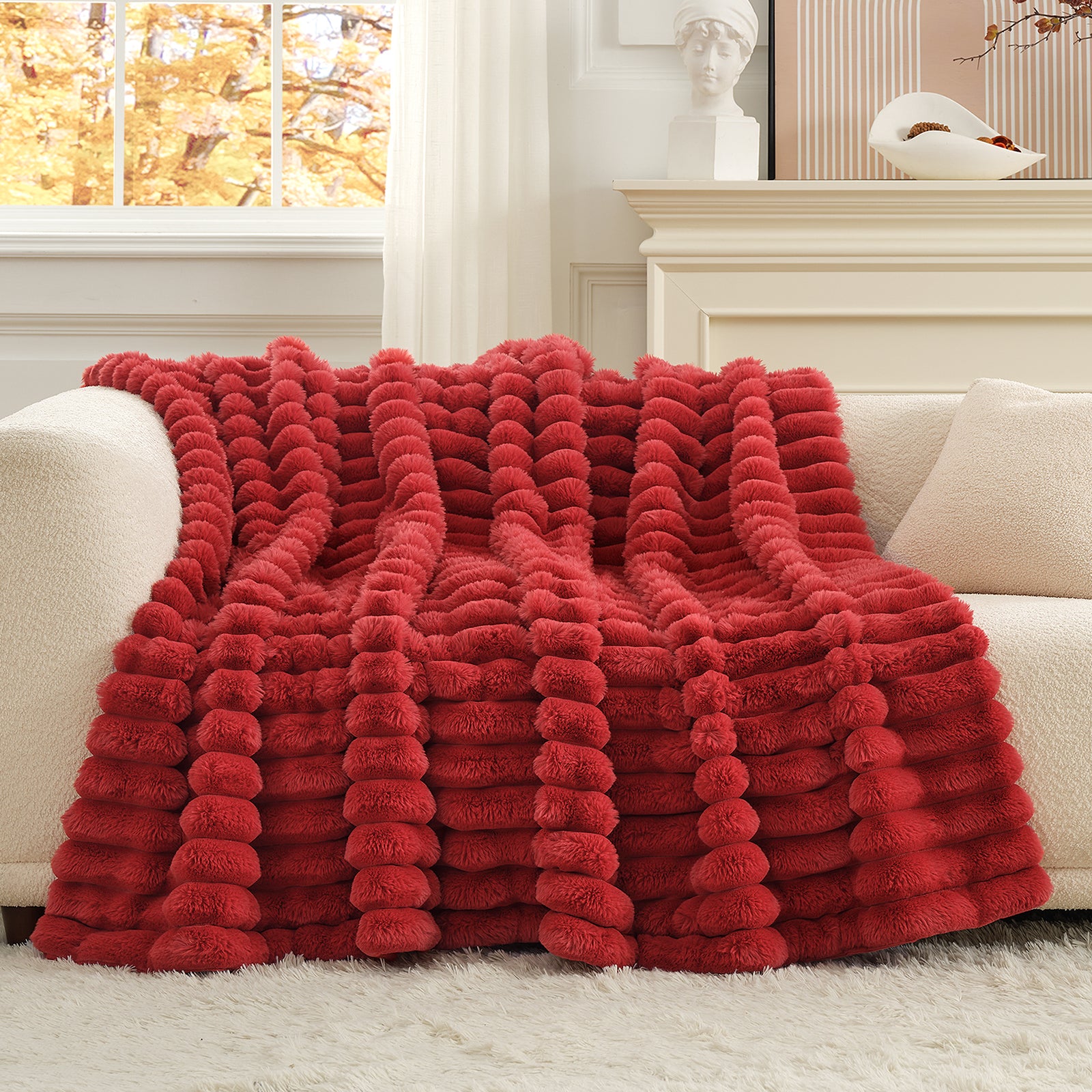 Red textured blanket draped over a white sofa in a cozy living room. #color_Cardinal Red