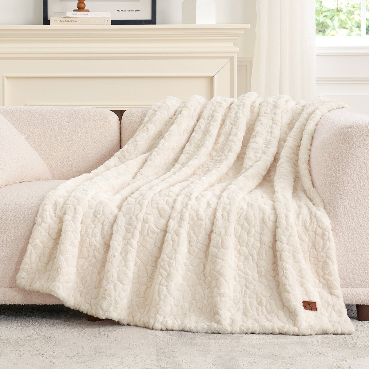 White textured blanket draped over a beige sofa in a bright room. #color_Cream White