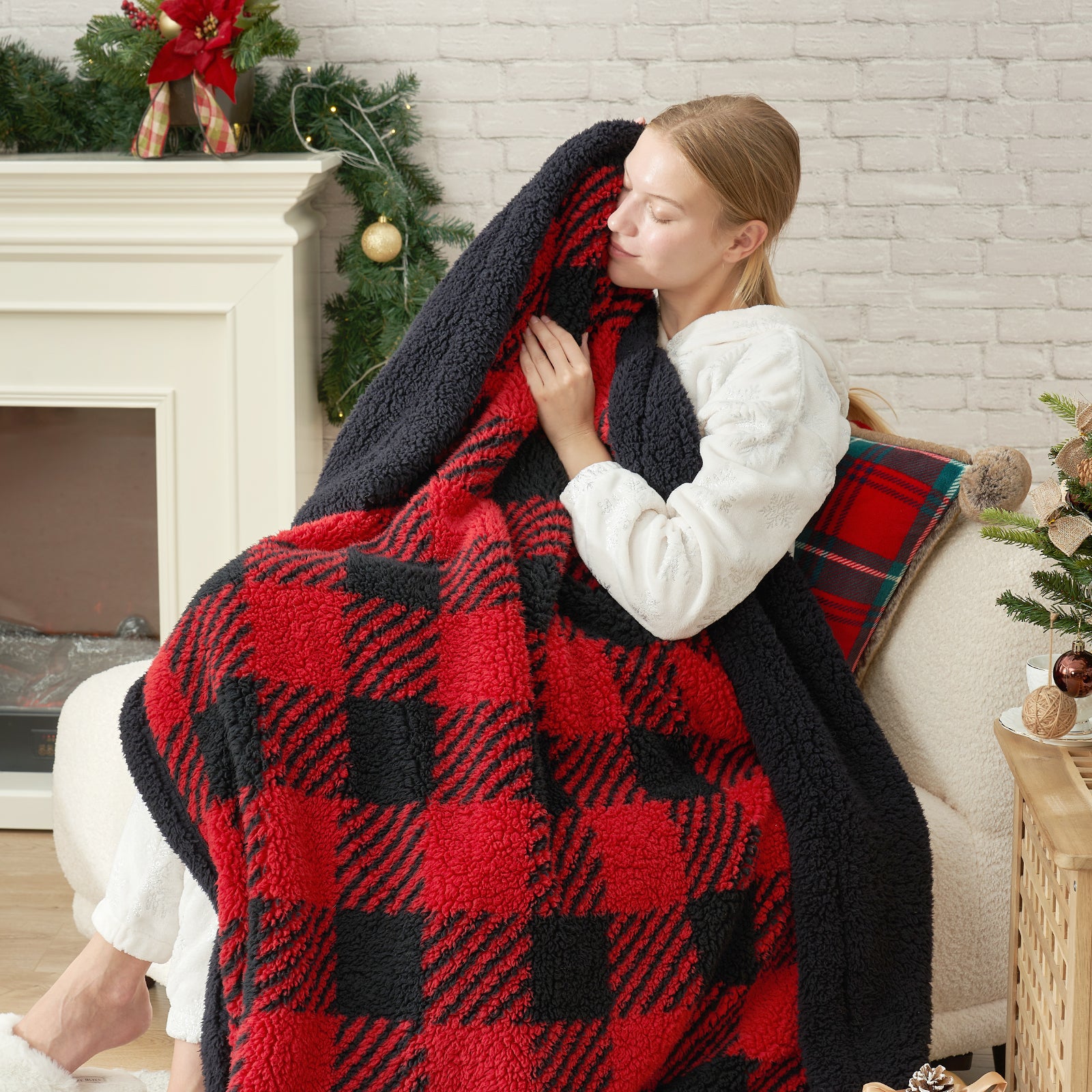 Woman wrapped in a red and black plaid blanket in a cozy living room. #Color_Red/Black Buffalo Check