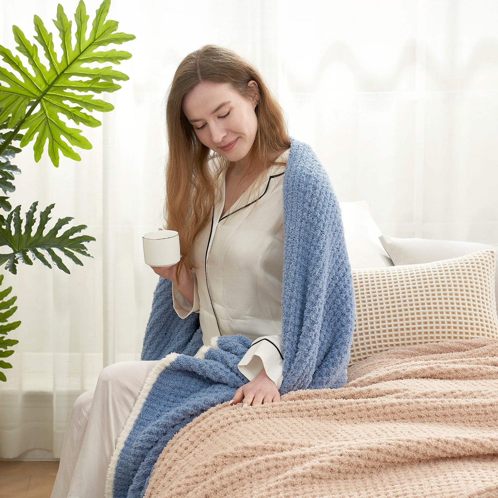 Woman enjoying a cup of coffee with a Soft Waffle Feather Yarn Throw Blanket in Dark Blue in a bright room setting. #color_Dark Blue