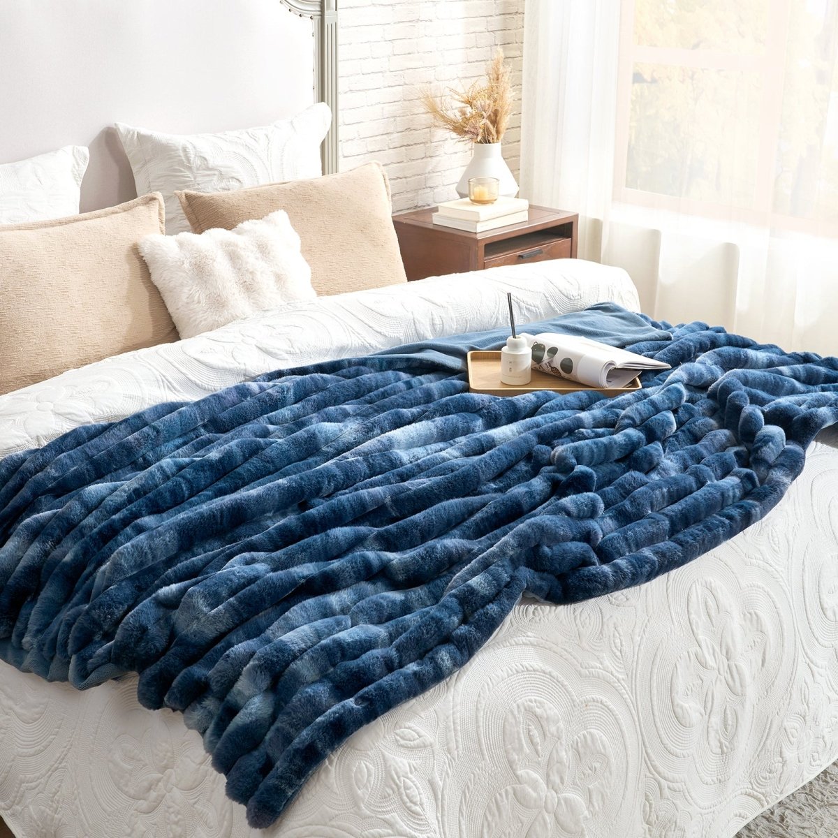 Blue blanket draped over a white bed in a bedroom setting. #color_Tie-dye Blue
