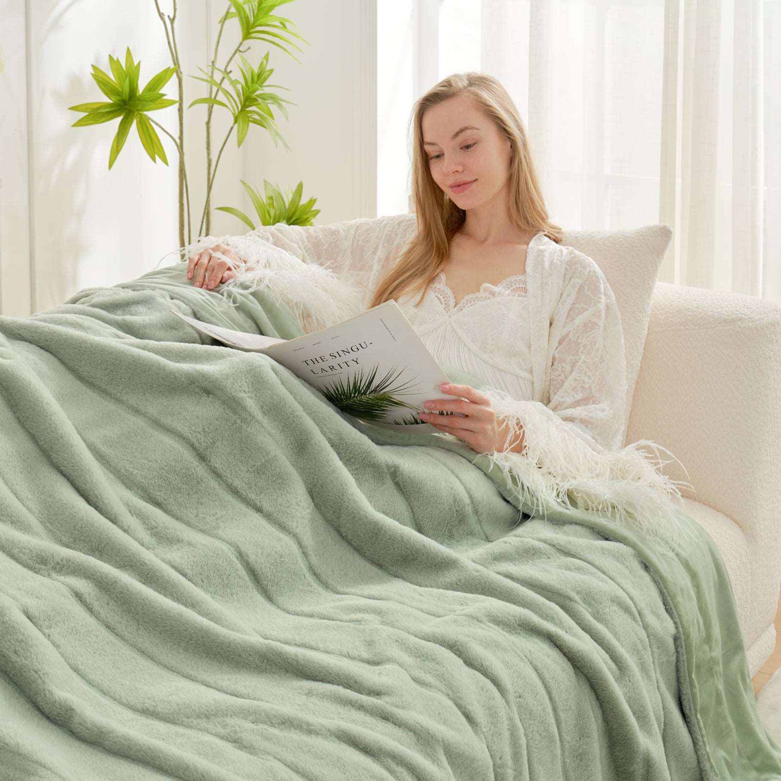 Woman relaxing with a Cozy Bliss green faux fur throw blanket, reading #color_Sage Green