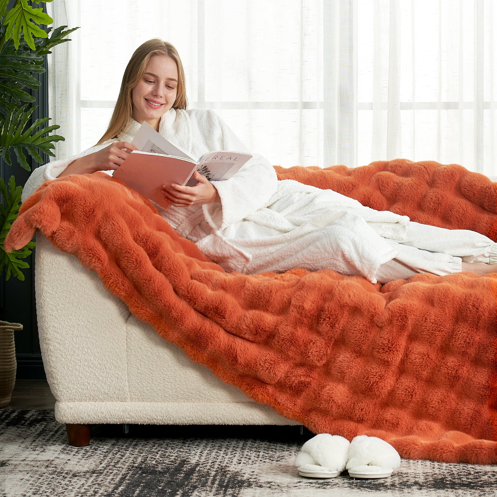Cozy Bliss orange bubble faux fur blanket on a couch, woman reading, premium comforter #color_Burnt Orange