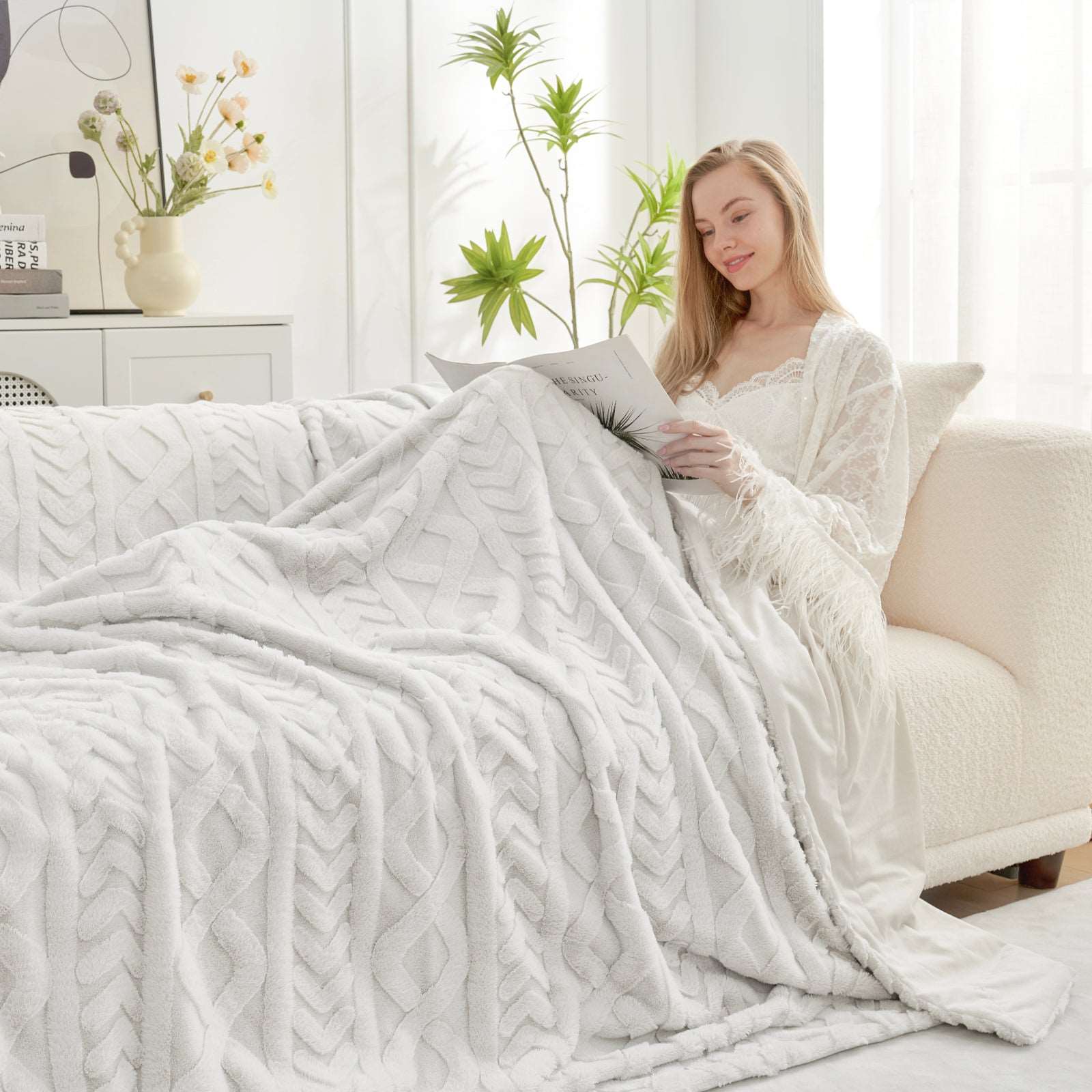Woman relaxing on sofa with cozy cable knit faux fur blanket, reading, cozy blanket #color_Beige