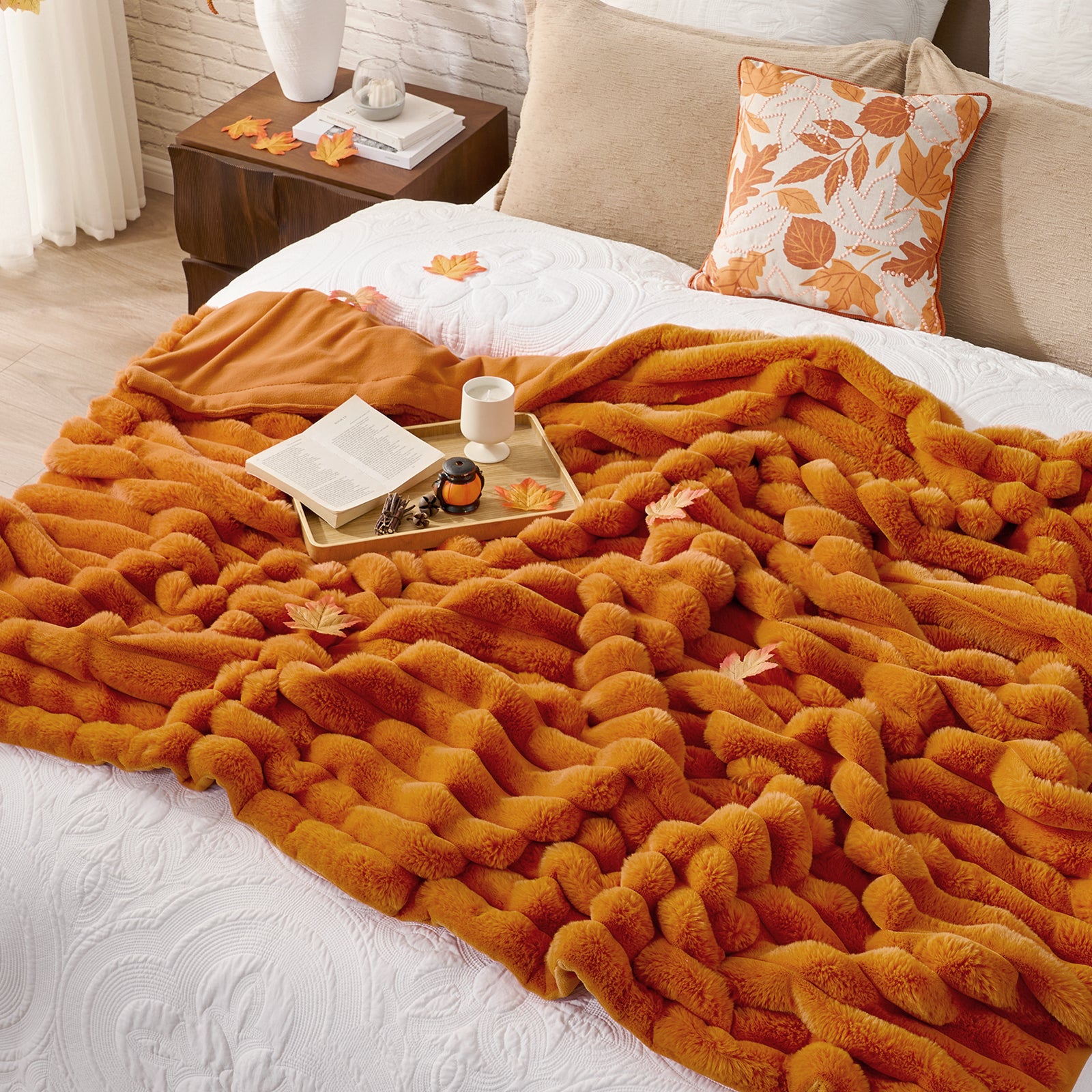 Orange blanket draped over a bed with a tray of items on a nightstand. #color_Burnt Orange