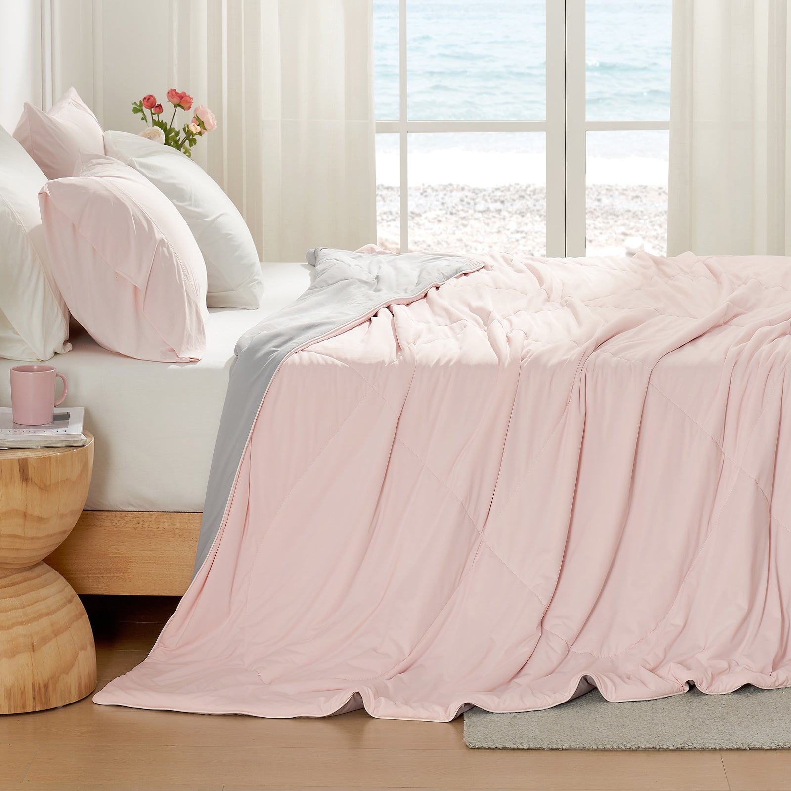 Light pink Cozy Bliss cooling comforter on bed, breathable bedding for hot sleepers, beach view. #Color_Pink/Grey