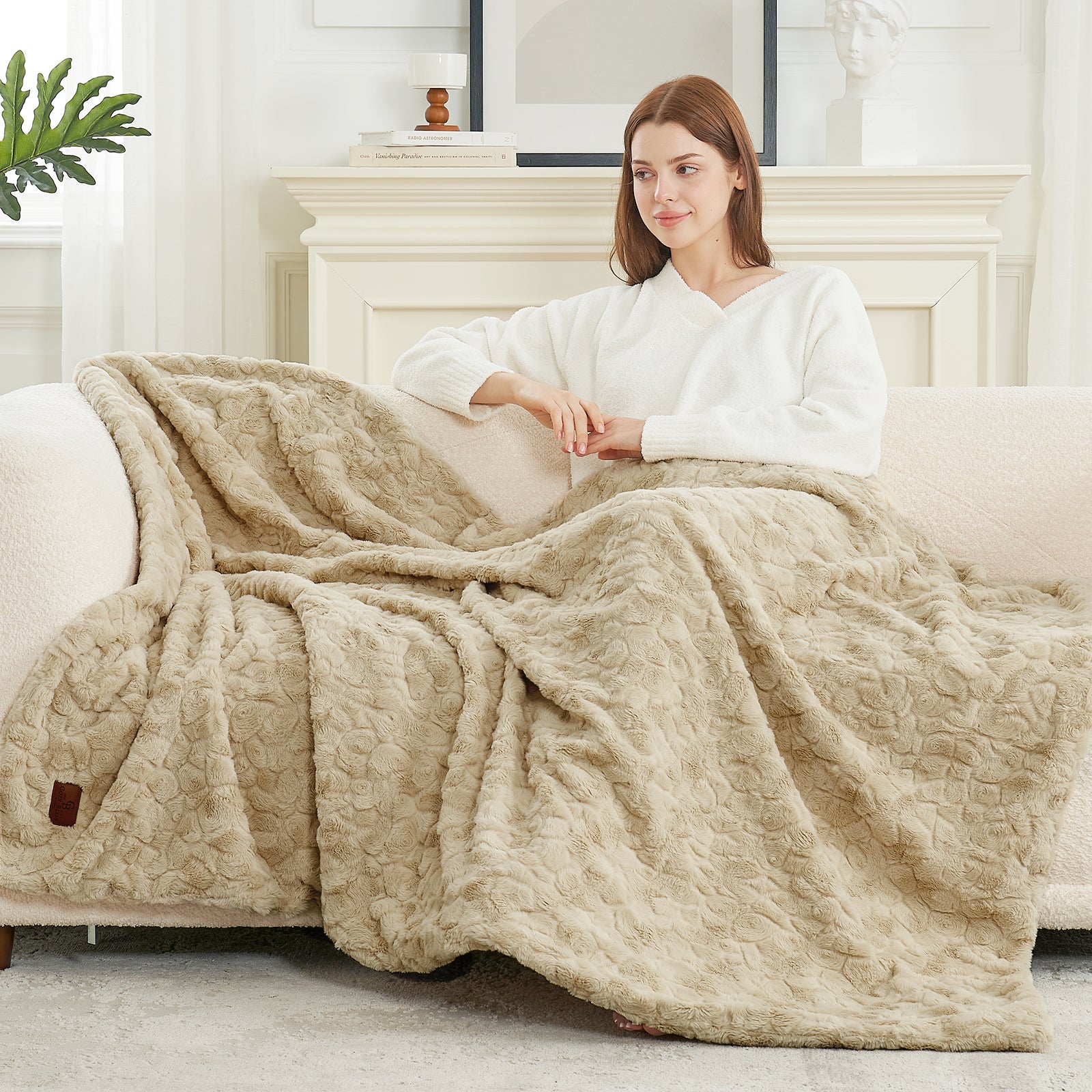 Woman sitting on a couch with a beige textured blanket draped over her, in a cozy living room setting. #color_Khaki
