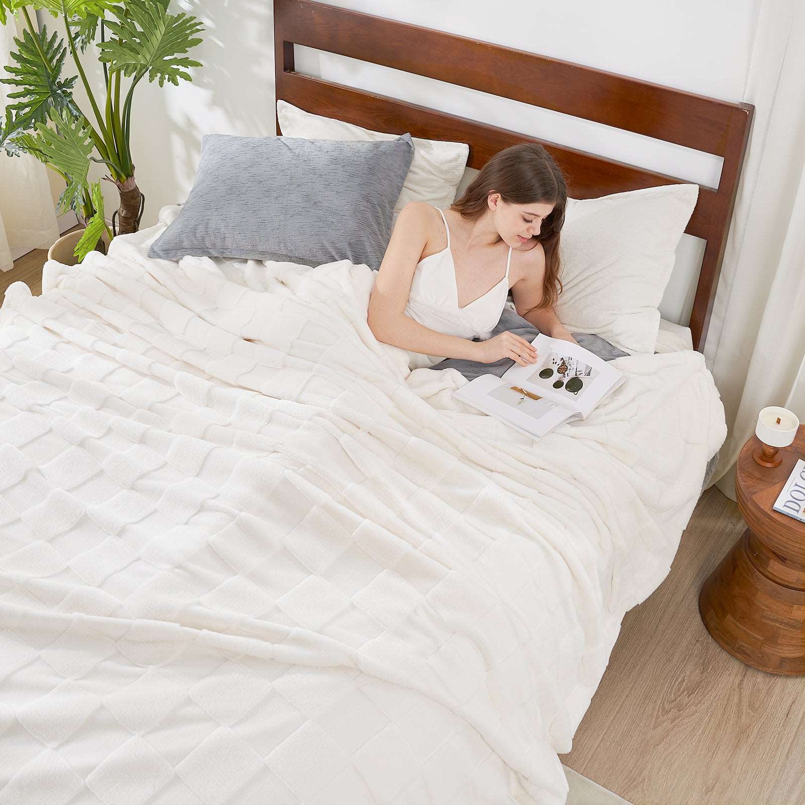 Woman relaxing with a white cozy blanket, reading a book. Soft, cozy blanket, perfect for bedroom decor. #color_Ivory