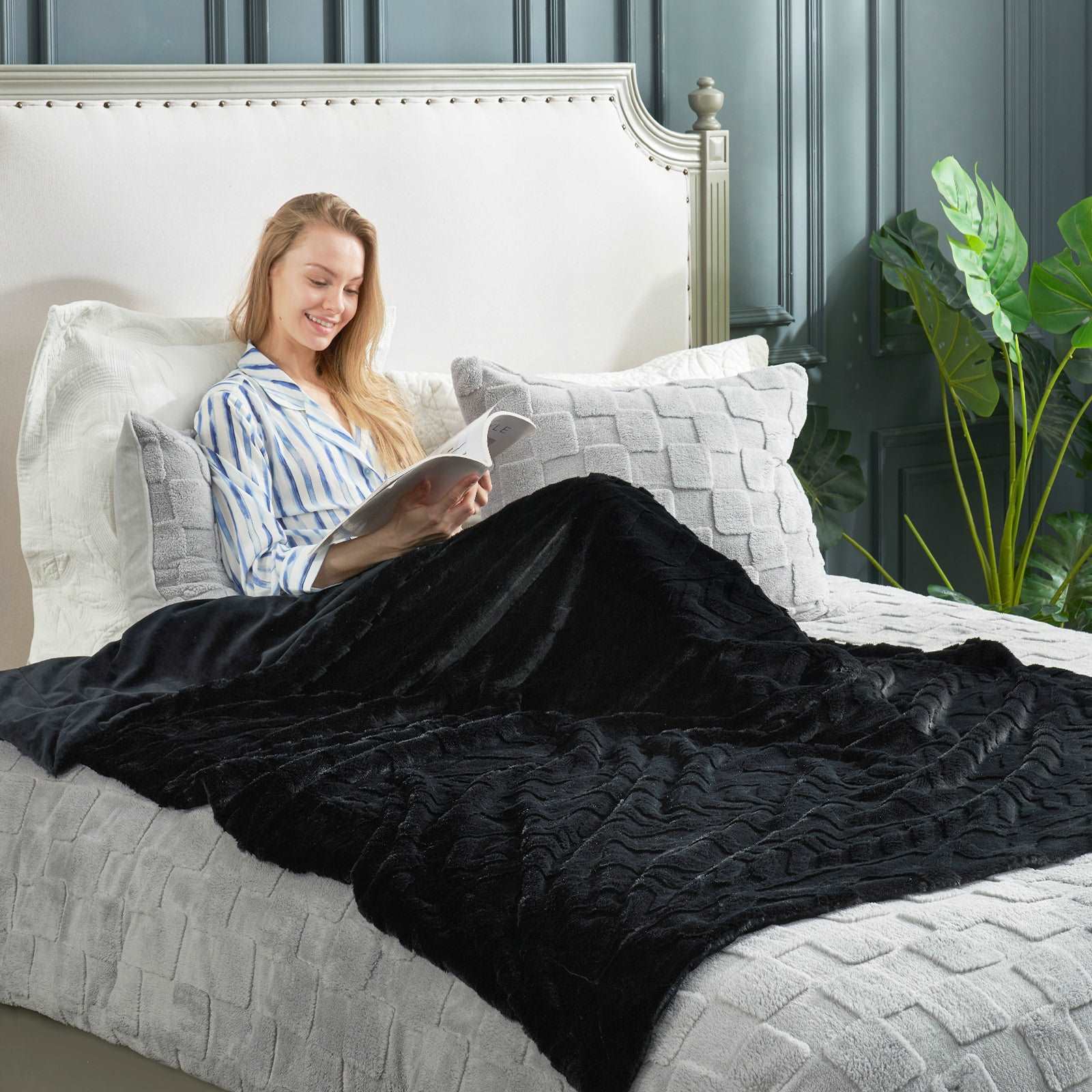 Woman reading in bed with a black faux fur throw blanket. Cozy and soft premium comforter for a relaxing sleep #color_Black