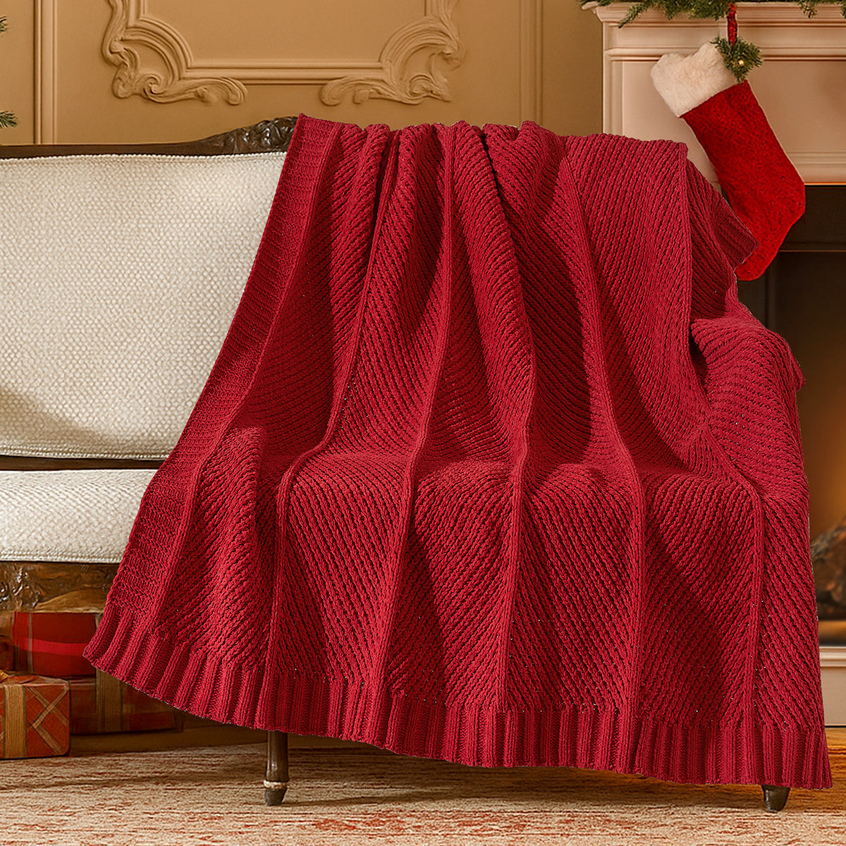 Red knitted blanket draped over a sofa in a festive living room with Christmas stockings and presents. #color_Christmas Red