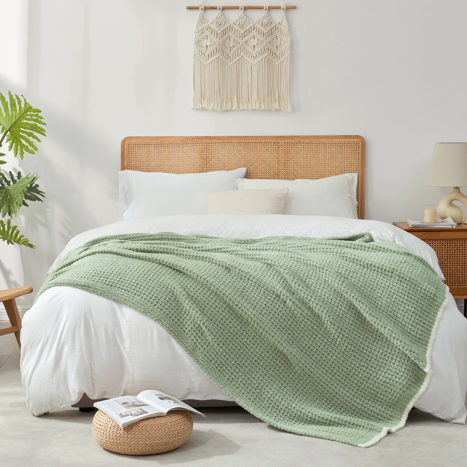 Bedroom with a bed featuring a green blanket, white pillows, and a woven headboard. #color_Sage Green