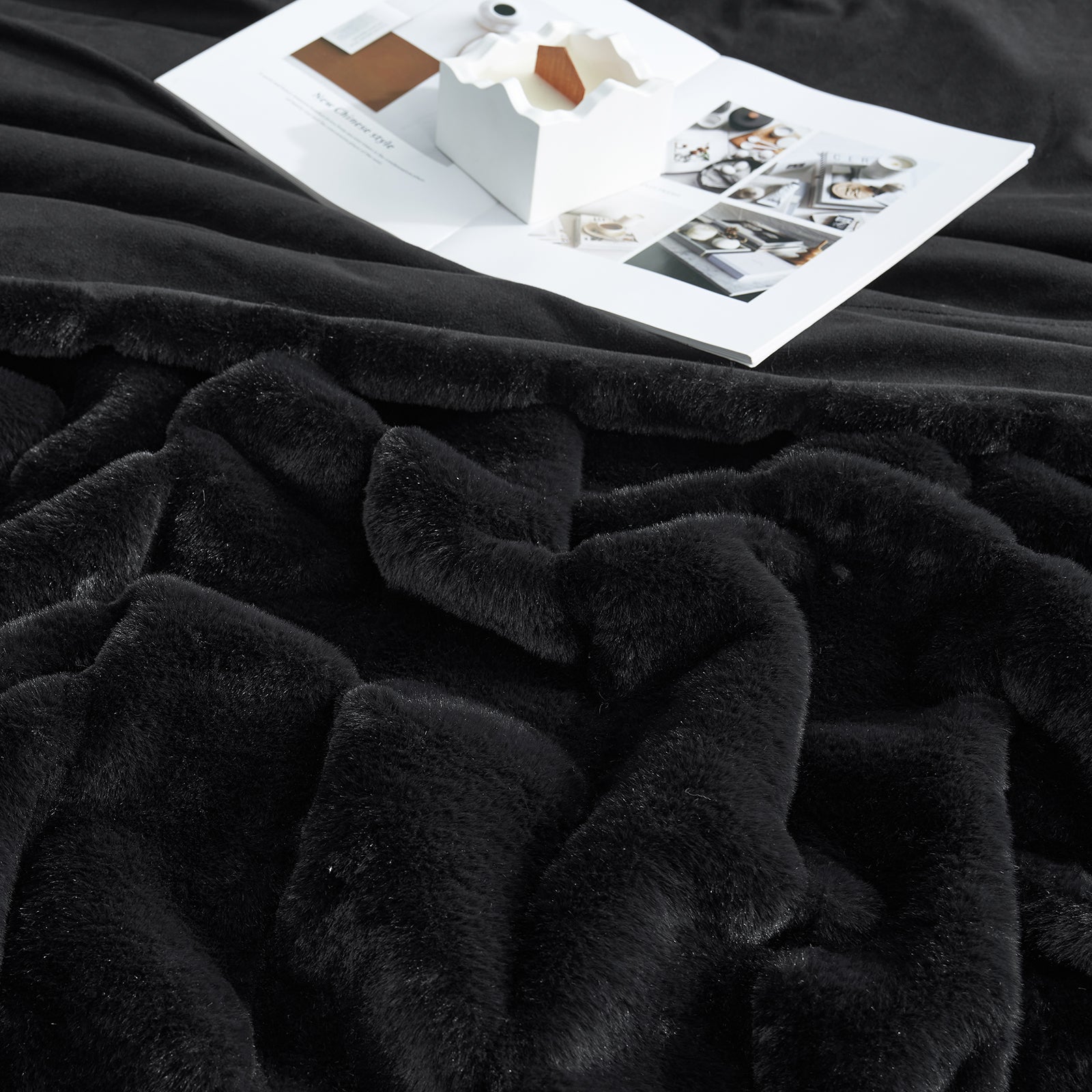 Black plush blanket with a magazine on top #color_Black