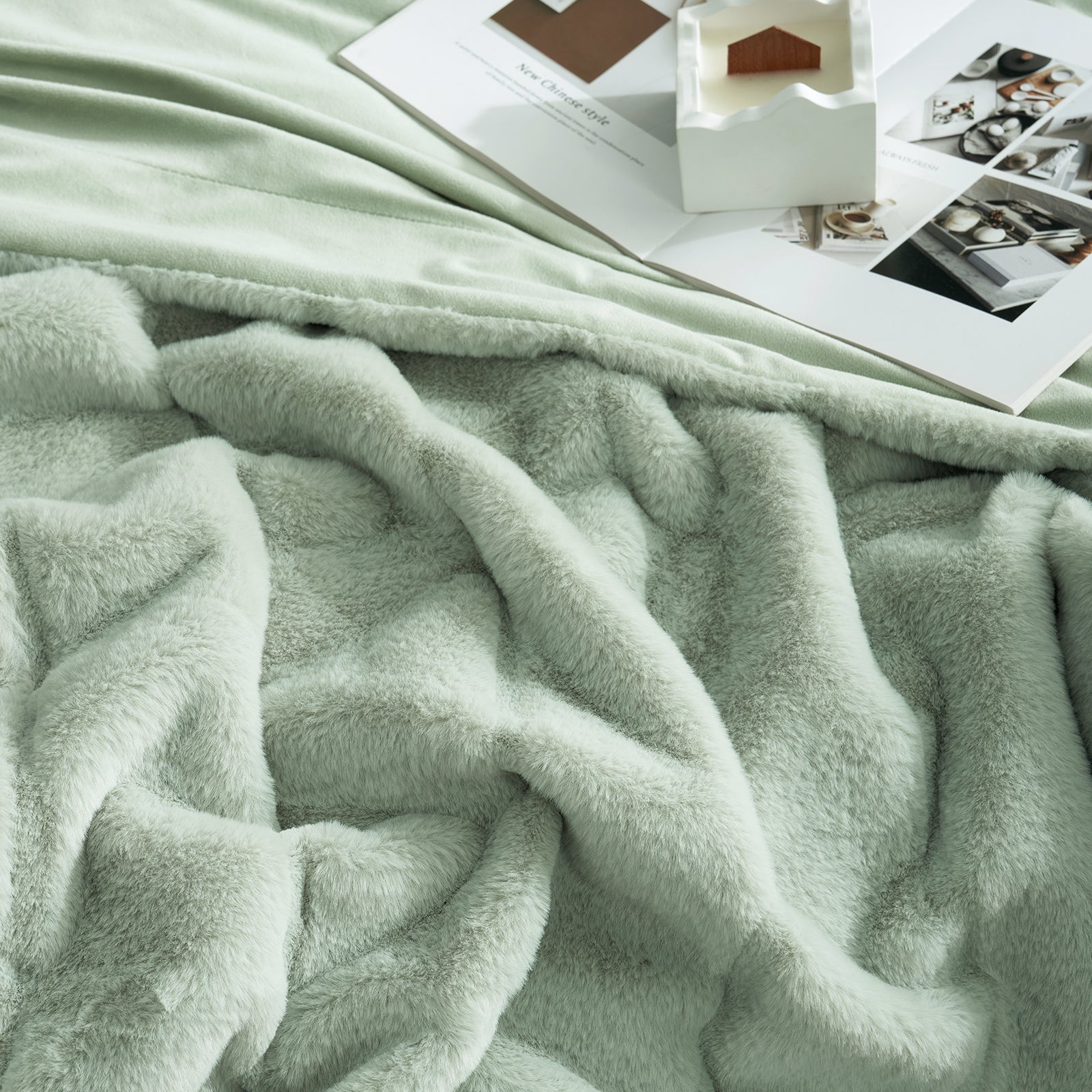 Light green blanket on a surface with books and photos in the background #color_Sage Green