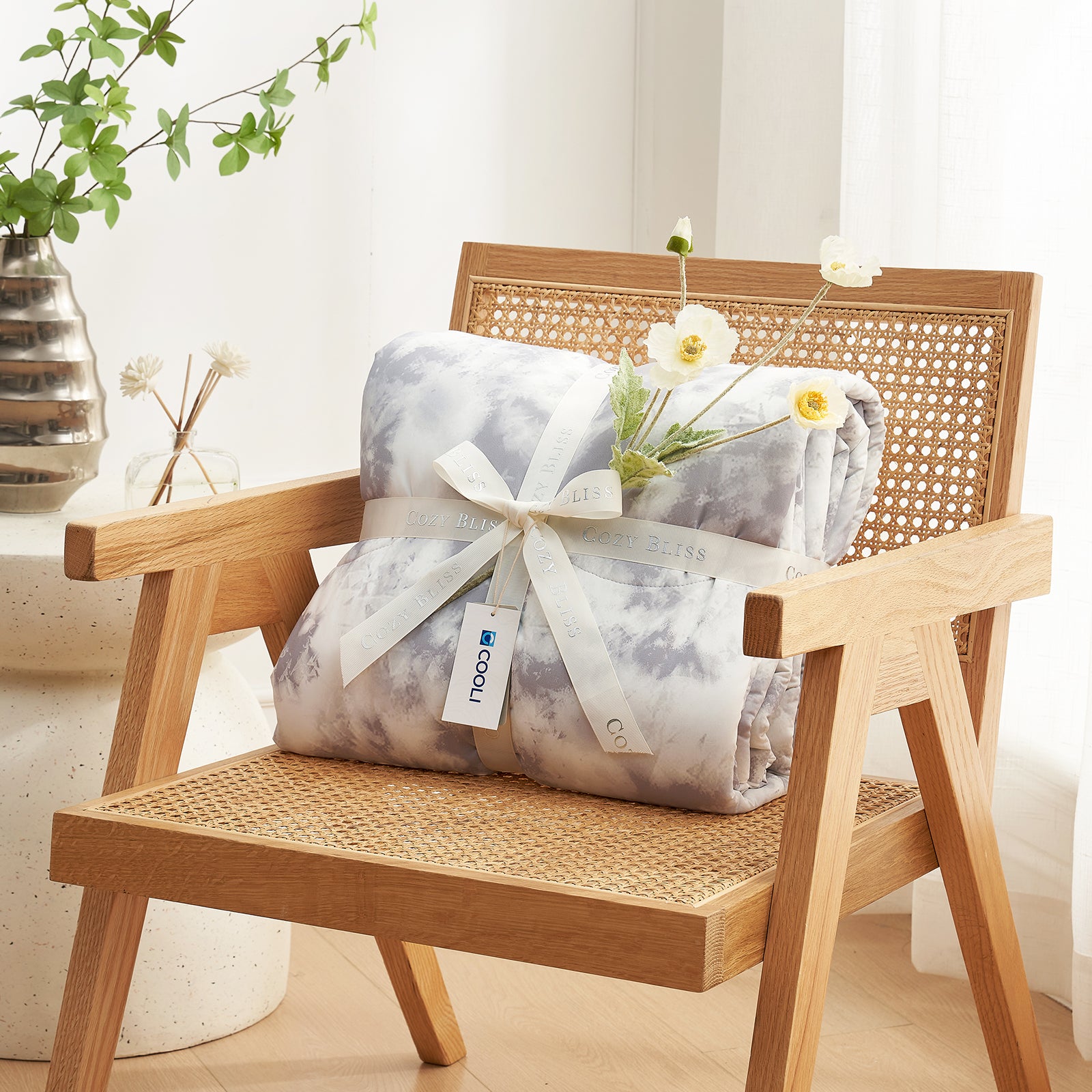 Woven chair with a wrapped gift and decorative flowers on a light background #Color_Tie-dye Grey