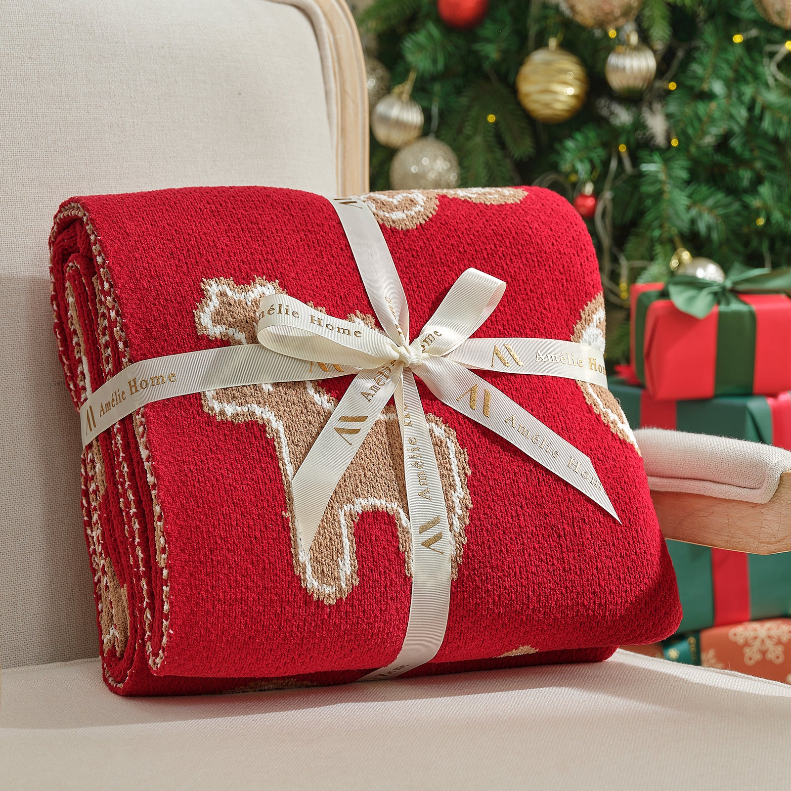 Red blanket with reindeer design and white ribbon on a couch with Christmas tree and presents in the background #color_Gingerbread Cookie