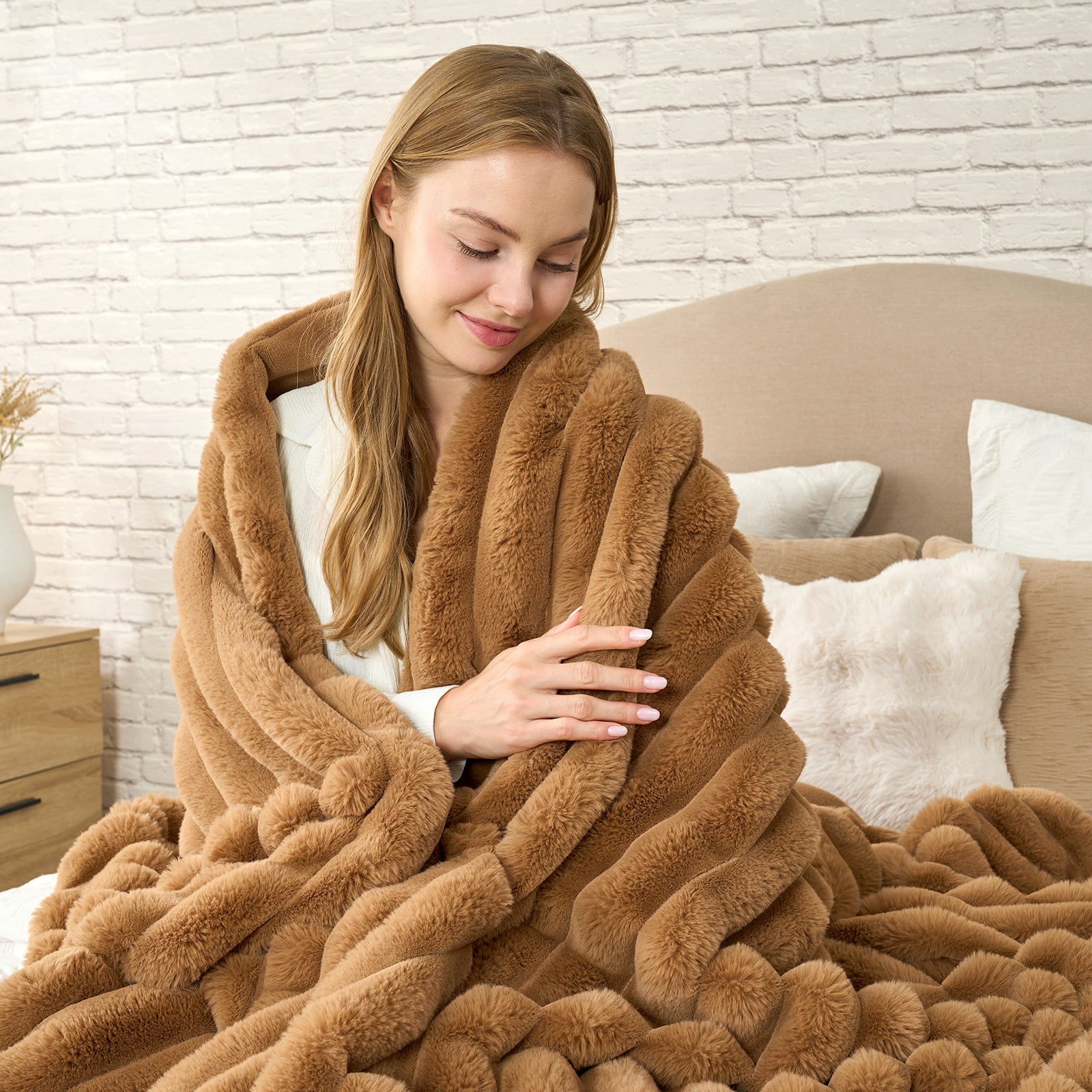 Woman wrapped in a brown fuzzy blanket in a cozy bedroom setting. #color_Toasty Brown