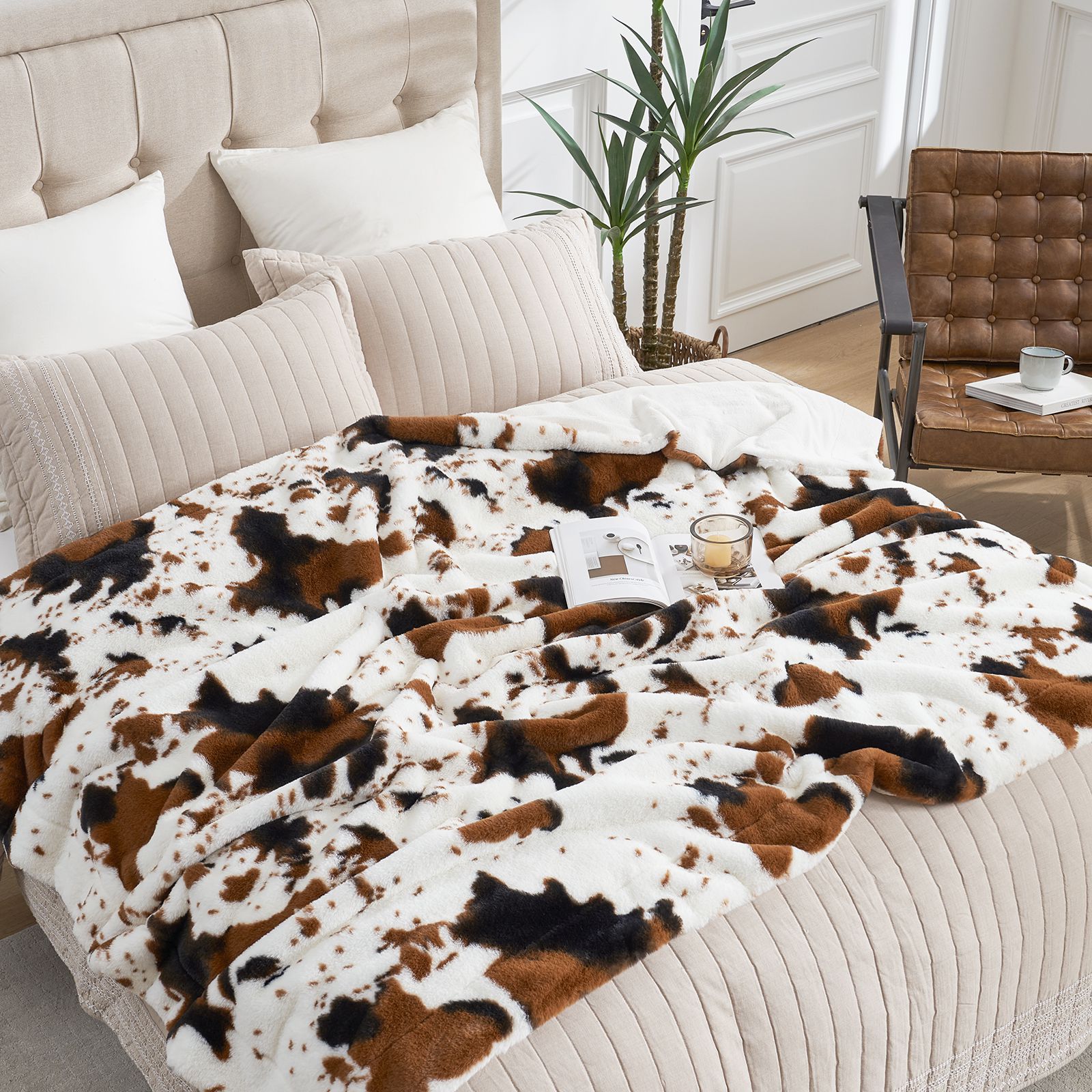 Cozybliss cow print faux fur blanket on bed. Luxurious and soft, perfect for bedroom comfort. #color_Black/Brown Cow