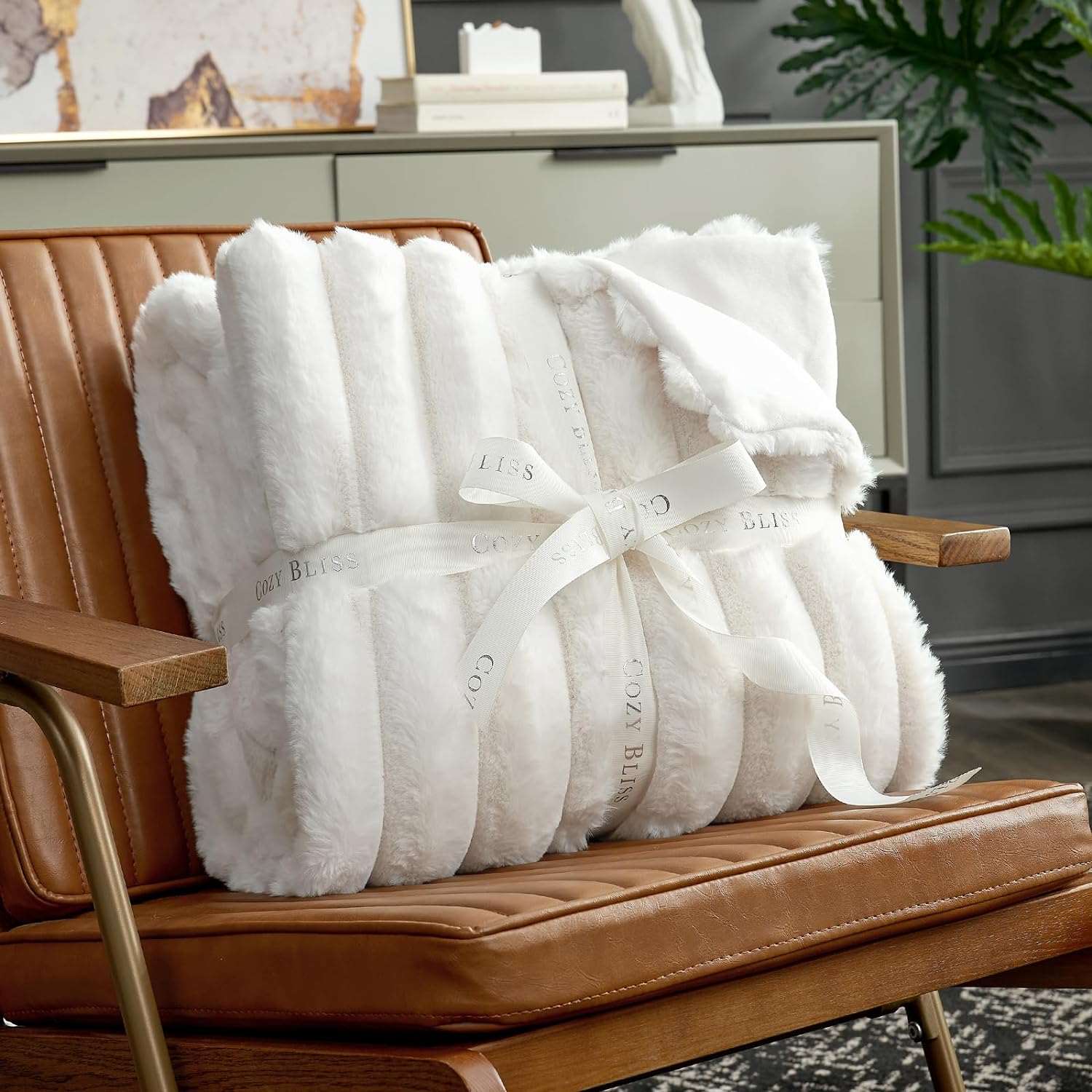 Cozy Bliss white faux fur blanket on a brown leather chair #color_Cream White