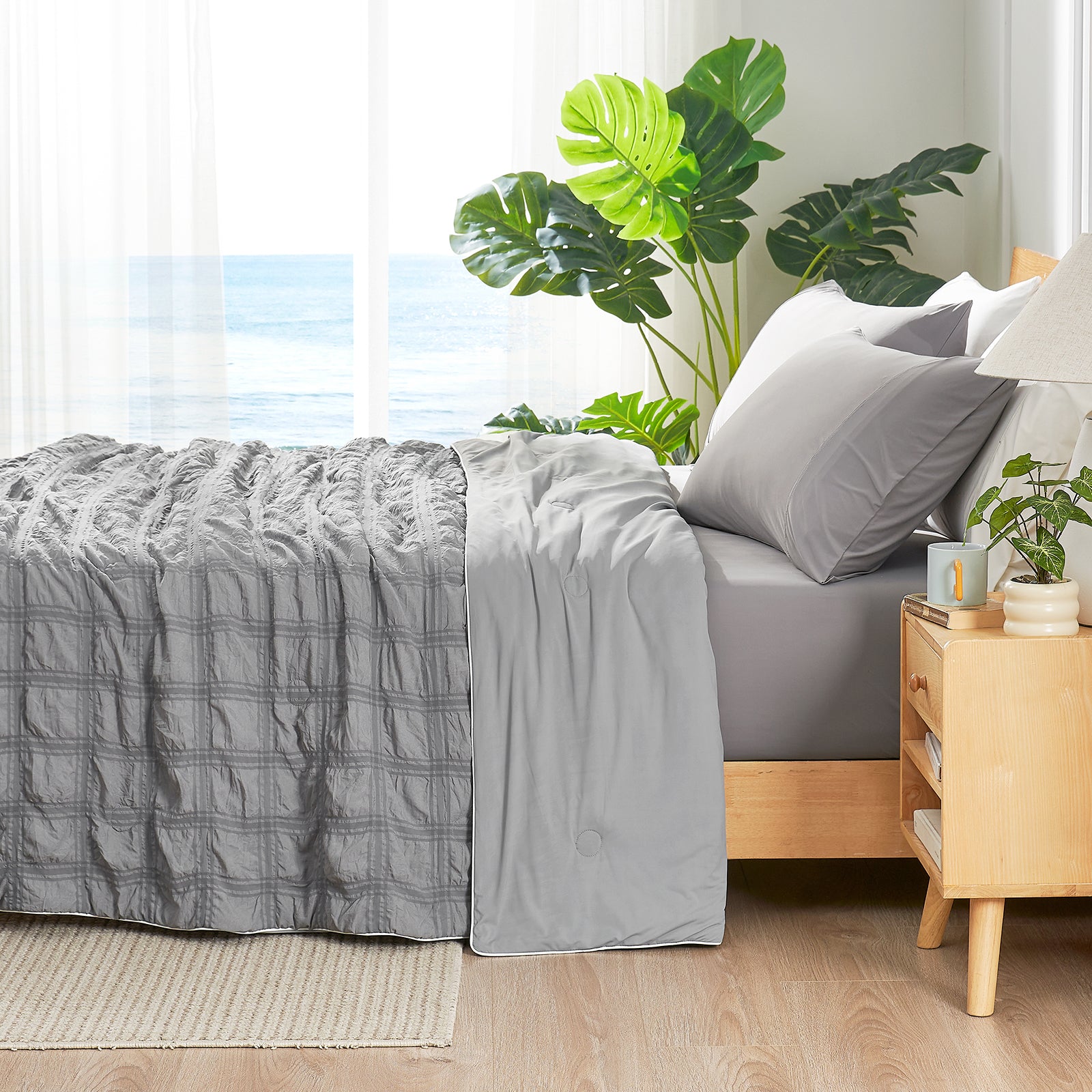 Gray bedding on a bed with a wooden nightstand and plants in a bedroom setting #color_Dark Gray