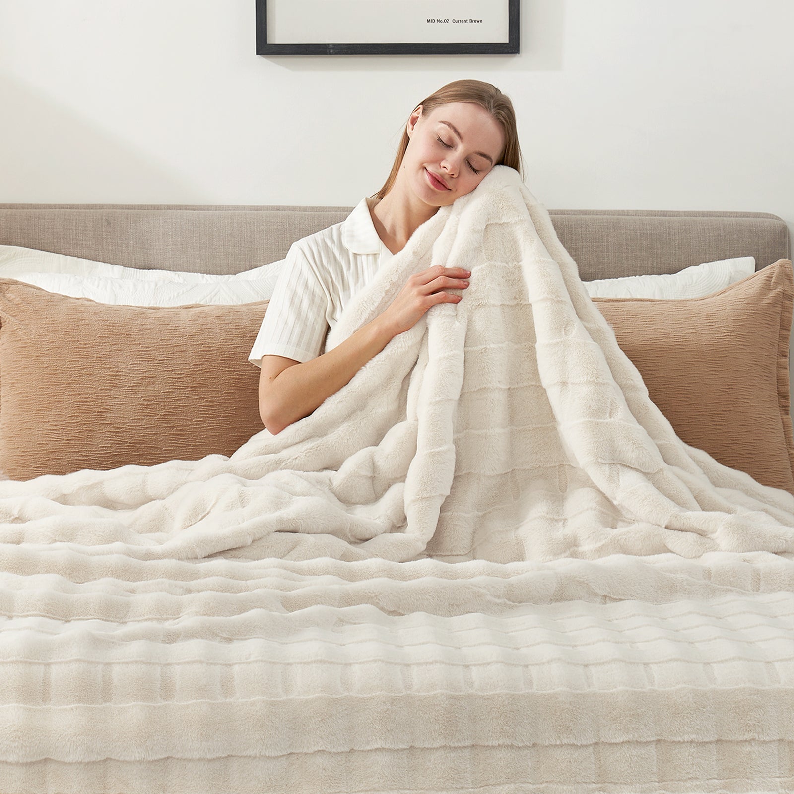 Woman embracing a cream-colored faux fur throw blanket on a bed, cozy and soft home decor. #color_Cream White