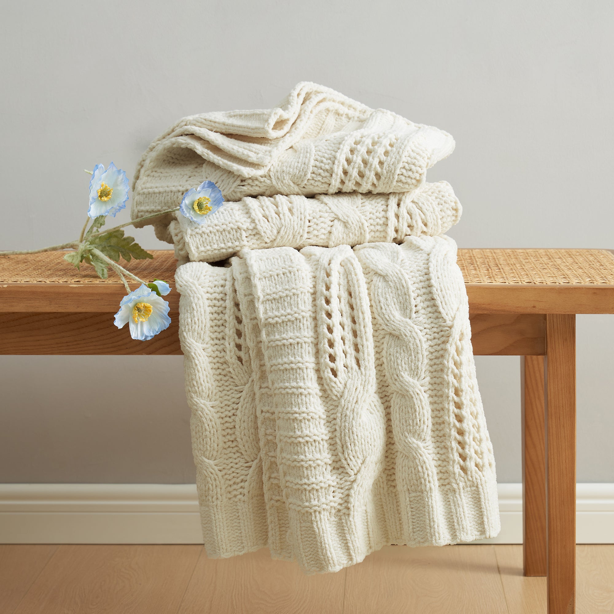 Chenille Cable Knit Throw Blanket in Ivory neatly folded on a table, showcasing detailed cable knit texture. #color_Ivory