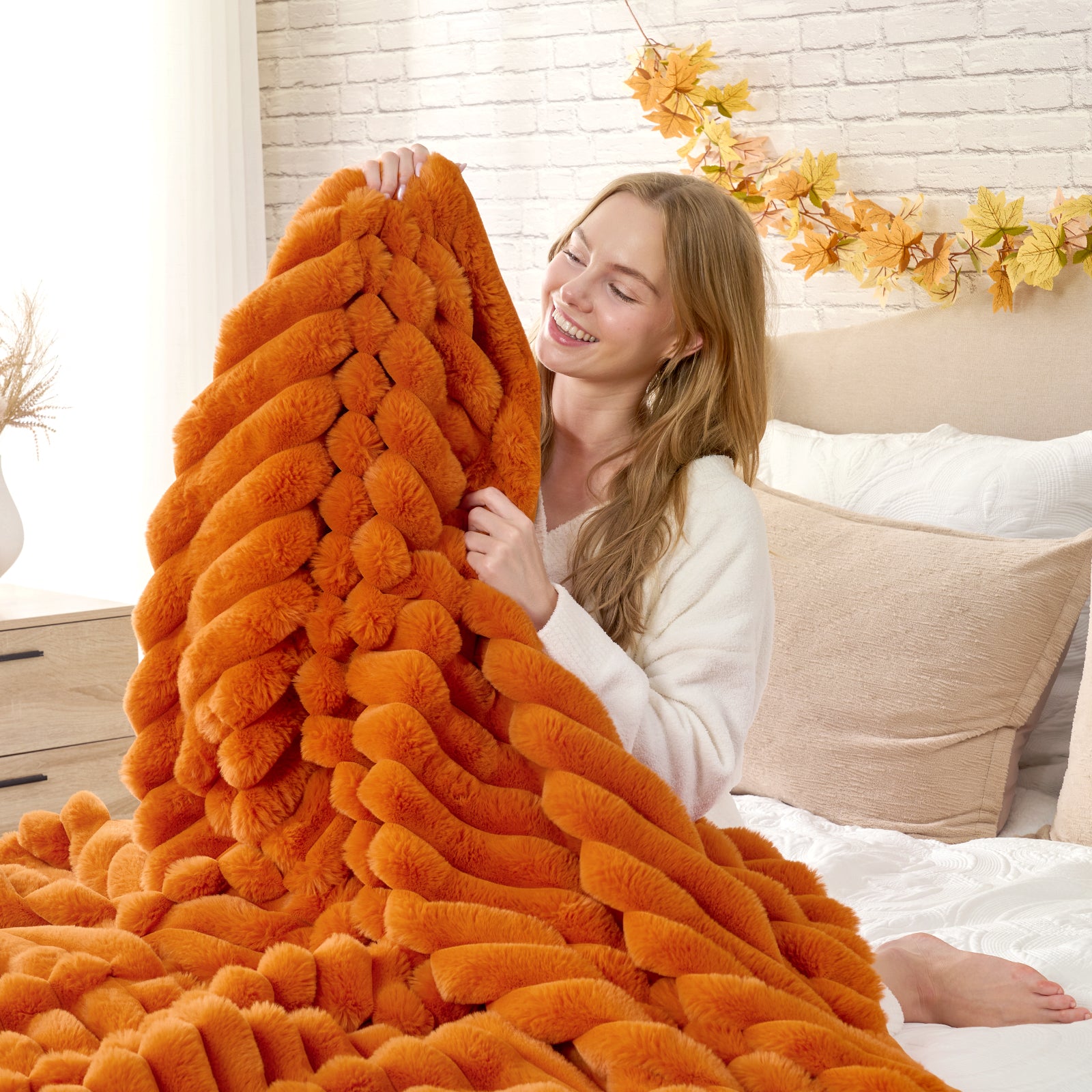 Woman holding an orange textured blanket in a cozy bedroom setting #color_Burnt Orange