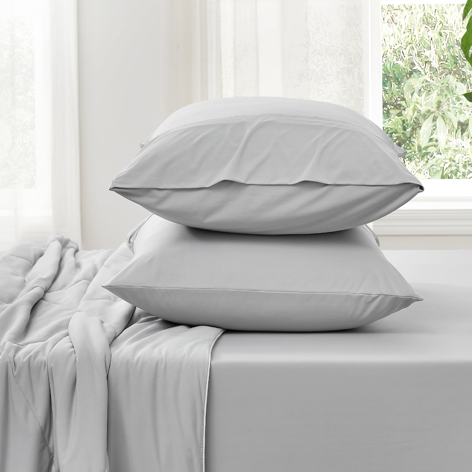 Light gray cooling fitted sheet set with pillowcases on bed. Cozy, ultra-soft, and breathable bedding. #Color_Light Grey
