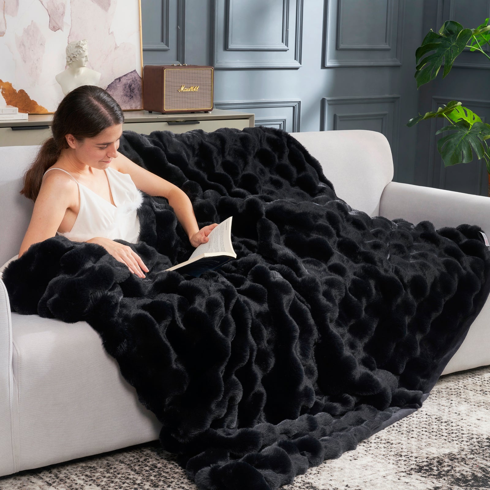 Women wearing Cozy Bliss black bubble faux fur throw blanket on a couch, perfect for a cozy, relaxing moment. #cozy bedding #color_Black