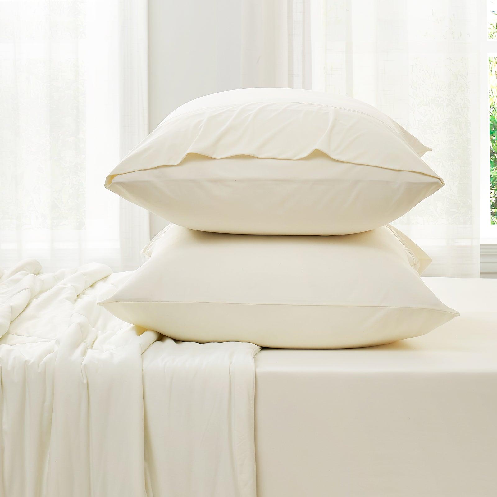 Cream-colored cooling pillowcases stacked on the bed, with sheets #Color_Cream White