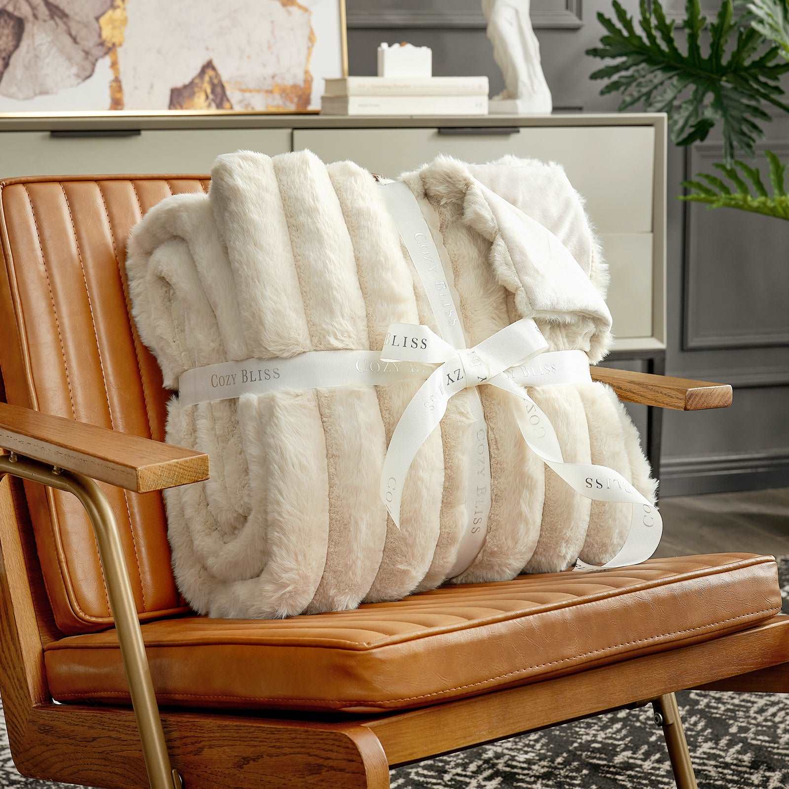 Cozy Bliss Striped Faux Fur Blanket in cream, tied with logo ribbon on a chair, for cozy comfort #color_Beige
