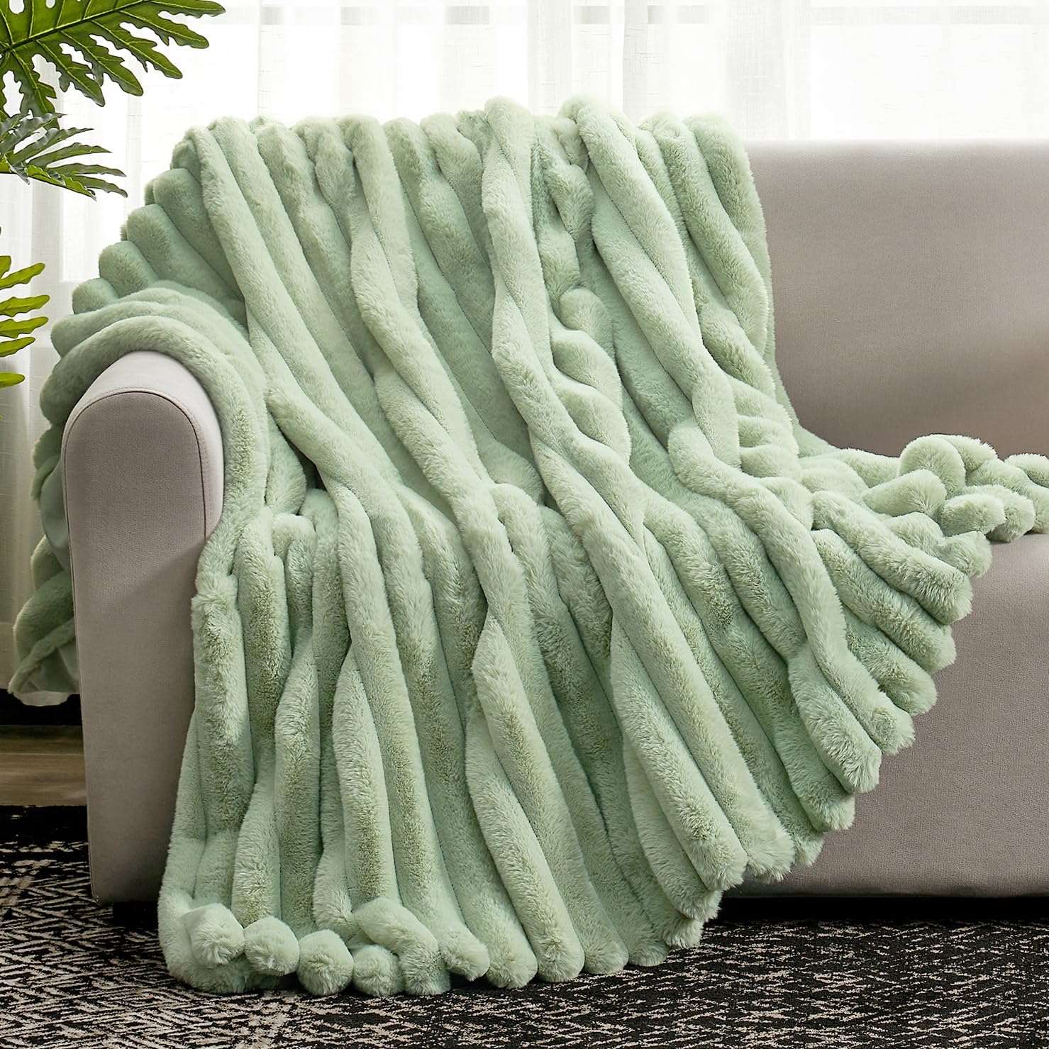 Sage green faux fur throw blanket draped over a sofa, cozy bedding. Soft and ultra-cozy blanket. #color_Sage Green