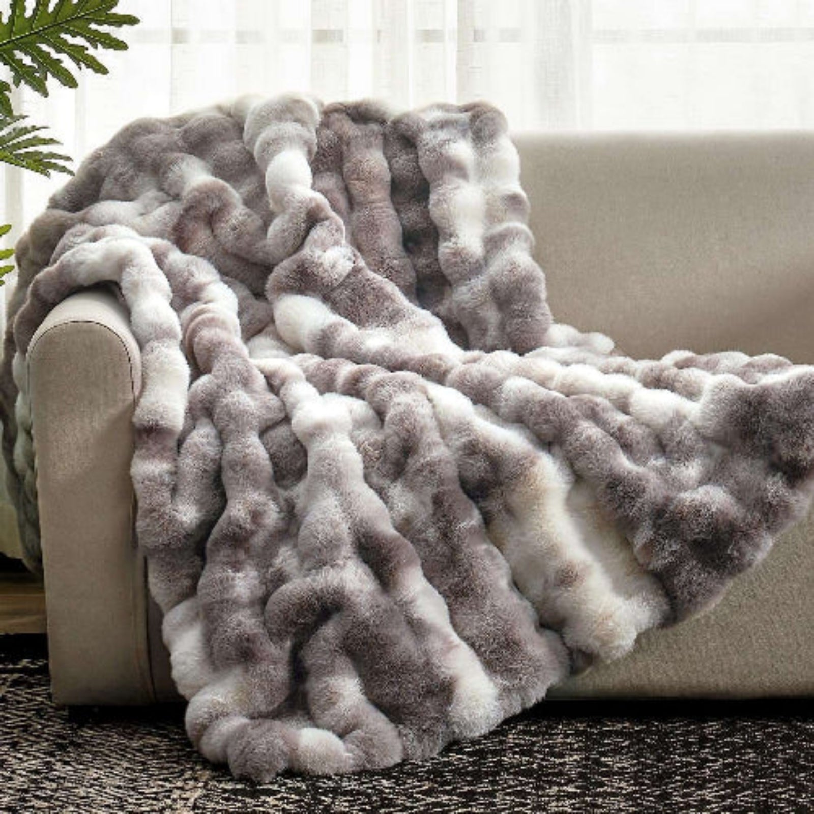 Cozy Bliss Bubble Faux Fur Throw Blanket in gray and white, draped over a sofa #color_Tie-dye Taupe