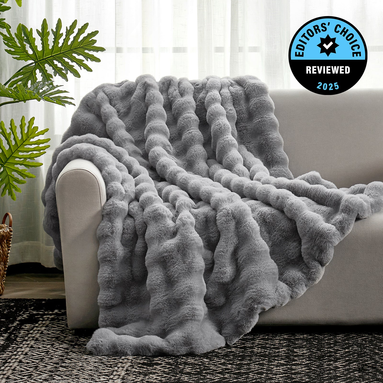 Gray textured blanket draped over a sofa with a plant and rug in the background, featuring an 'Editors' Choice' badge. #Color_Grey