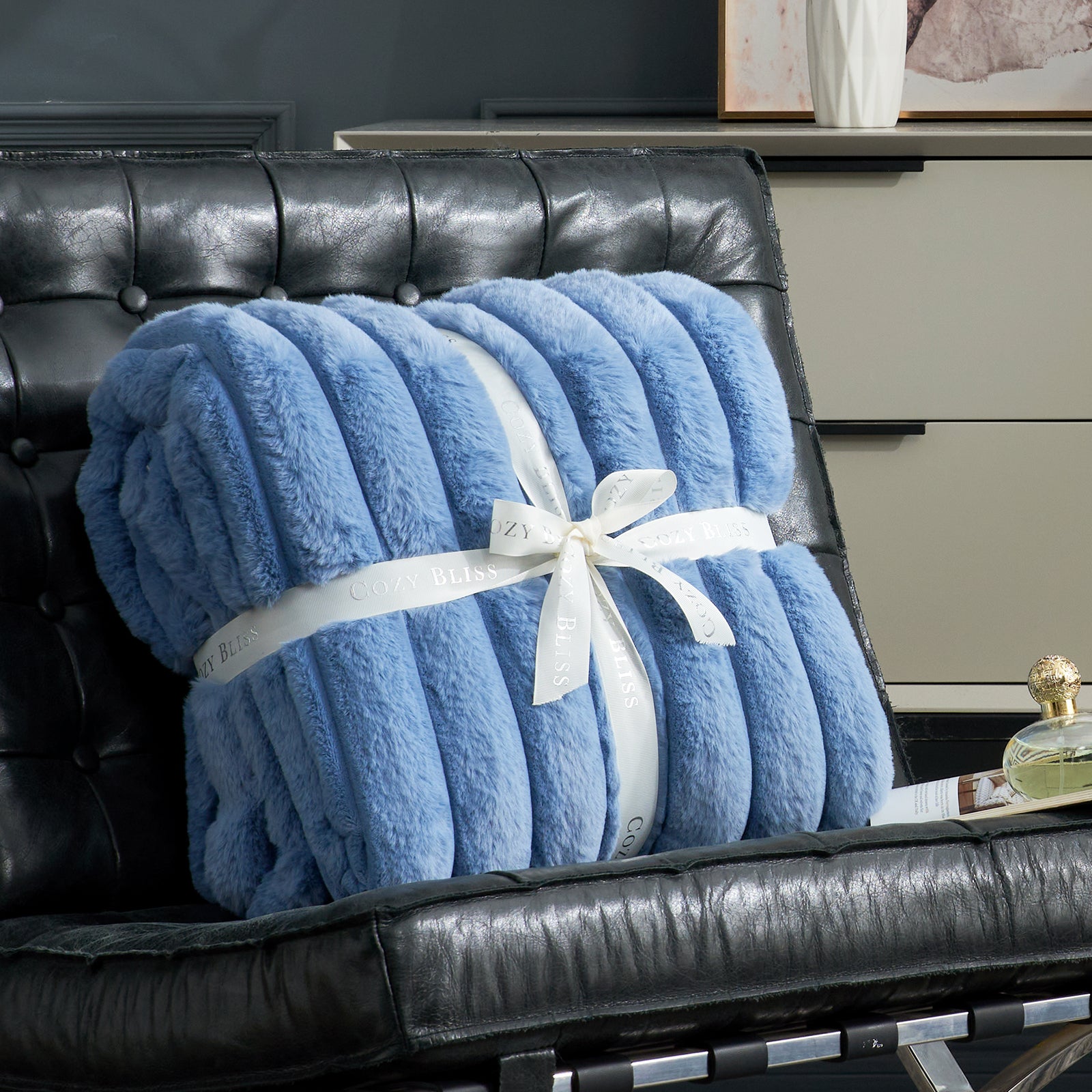 Cozy Bliss blue striped faux fur blanket on black leather chair, offering cozy comfort and style #color_Light Blue