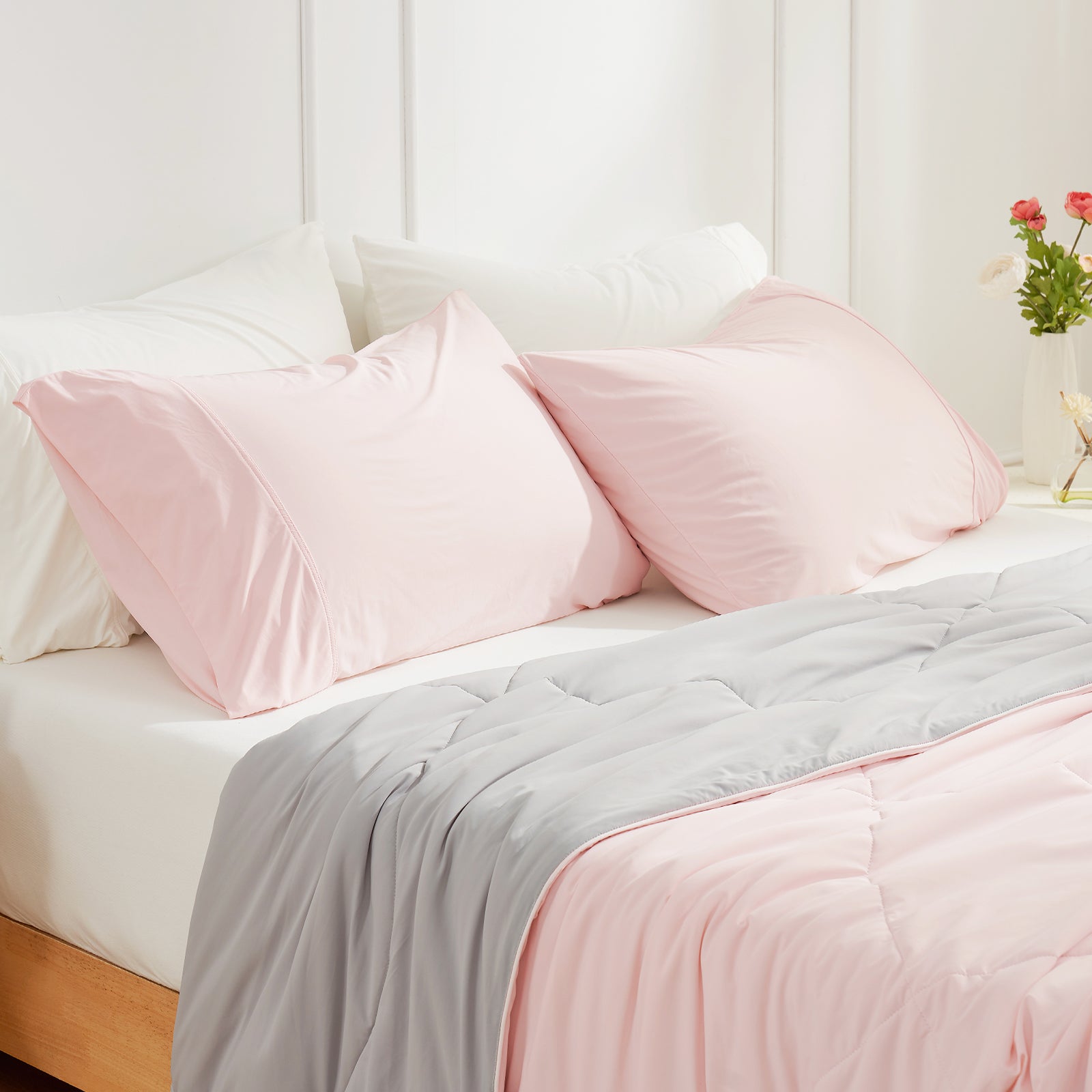 Pink cooling pillowcases on bed with gray comforter. Cozy breathable bedding for cool sleep. #color_Pink