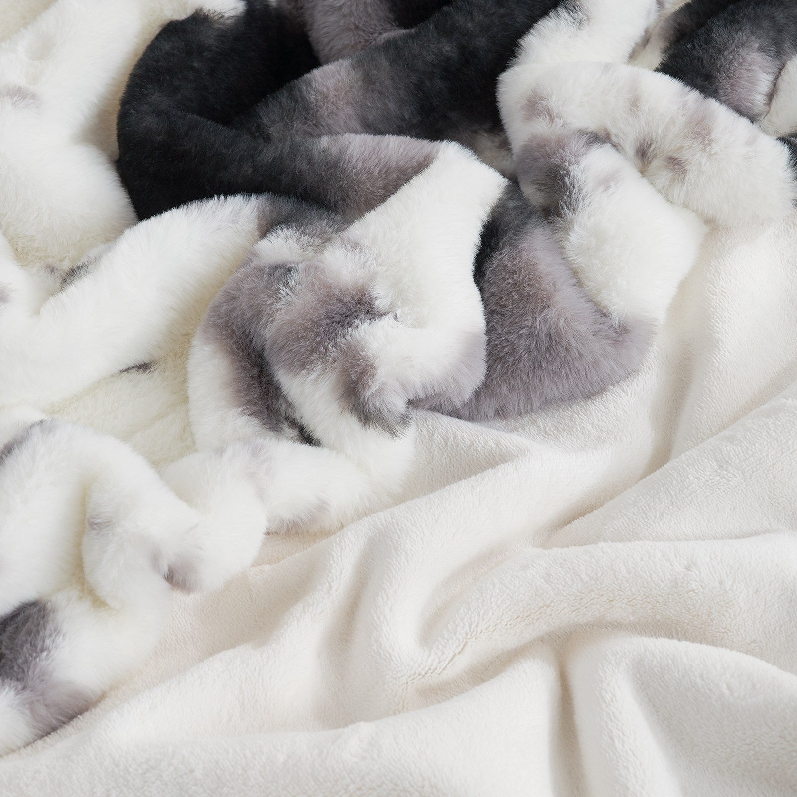 Cow print faux fur blanket close-up, soft texture, cozy blanket with black, gray, and white pattern. #color_Black/Grey
