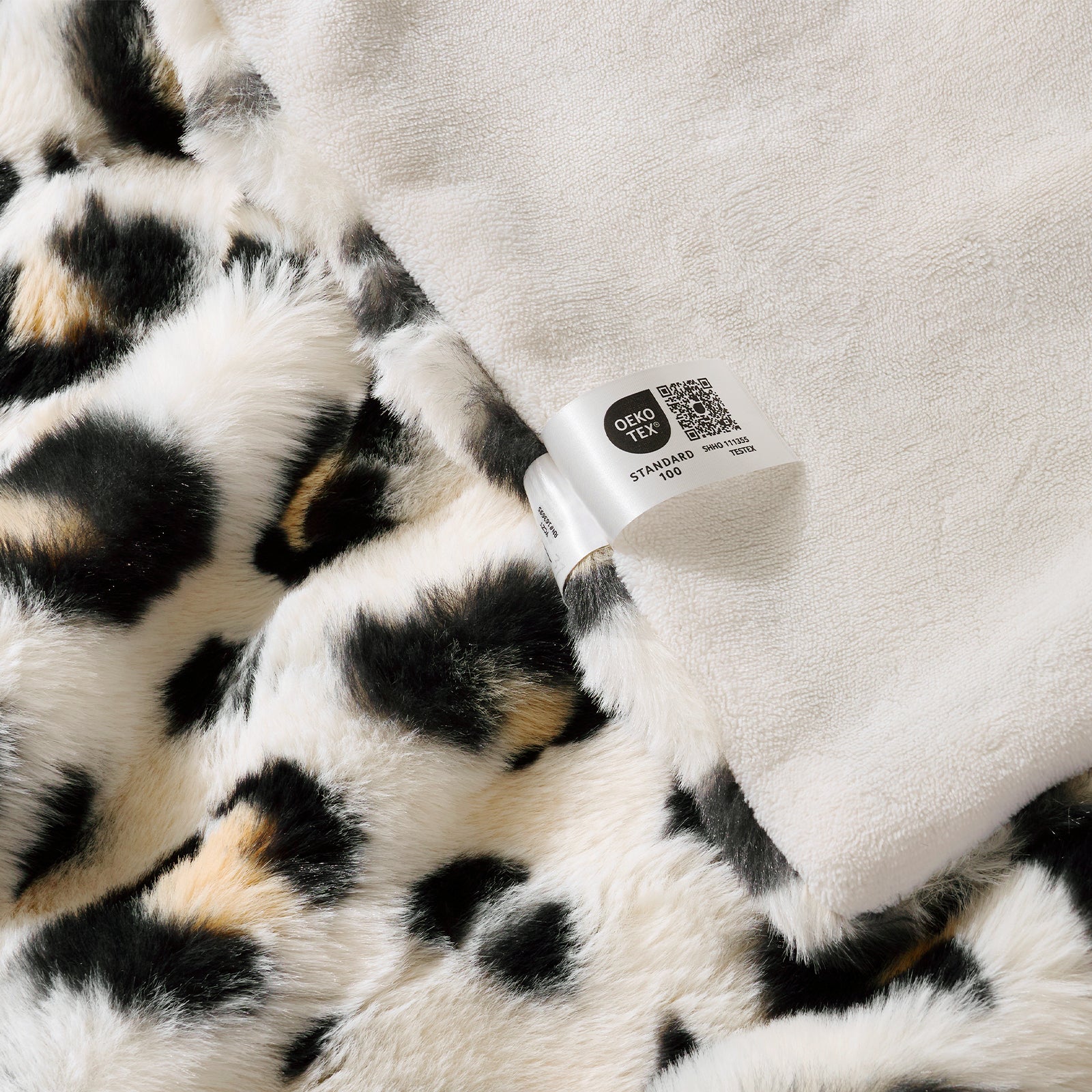 Close-up of a leopard print fabric with a OEKO-TEX Certified label. #Color_Leopard