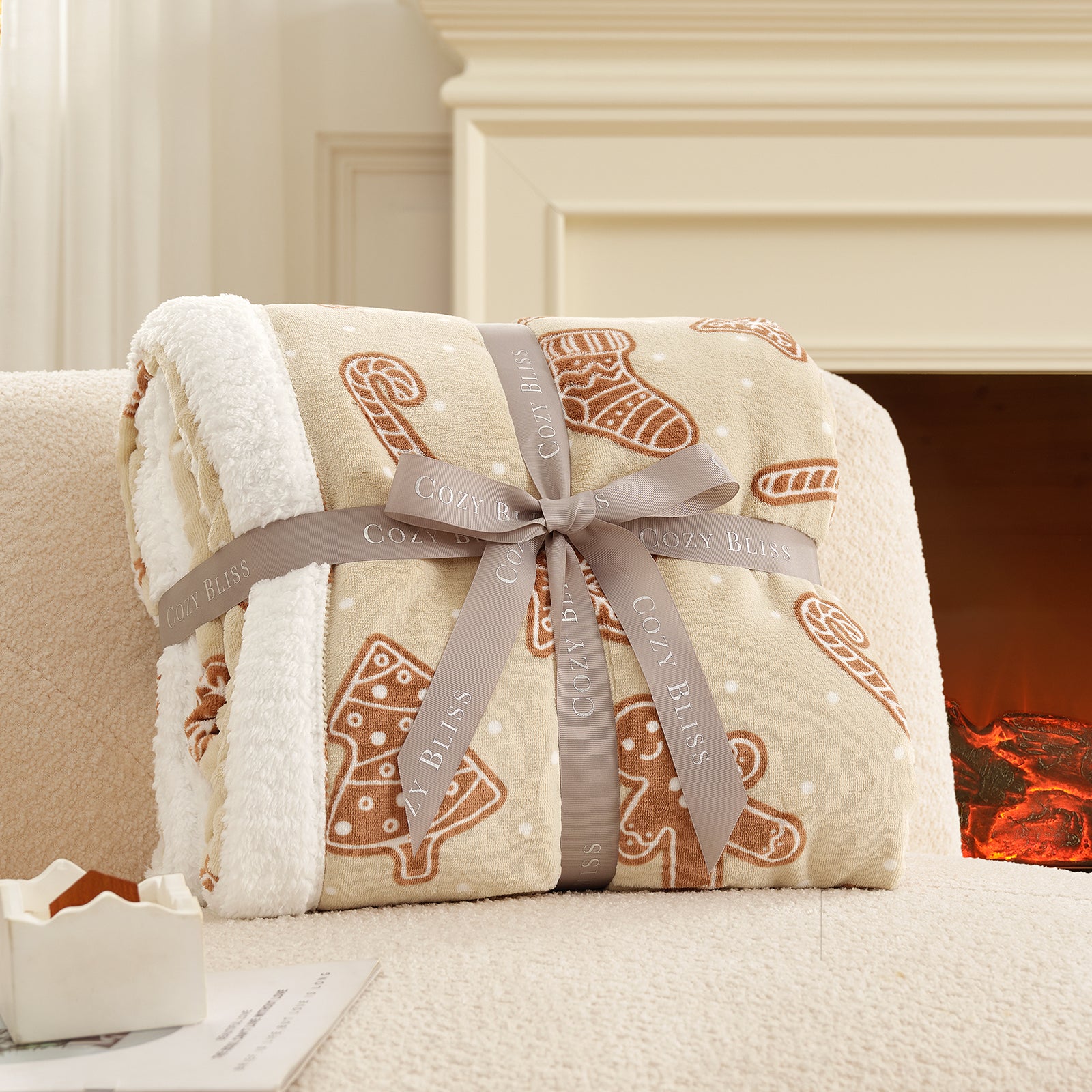Folded blanket with gingerbread design and ribbon, placed on a couch in front of a fireplace. #color_Christmas Gingerbread