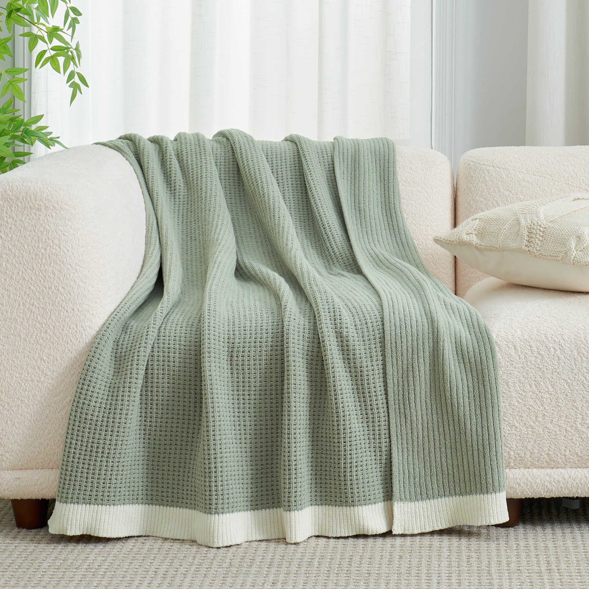 Chenille Waffle Knit Throw Blanket in Sage Green draped over a sofa, showcasing its soft tone and cozy texture. #color_Sage Green